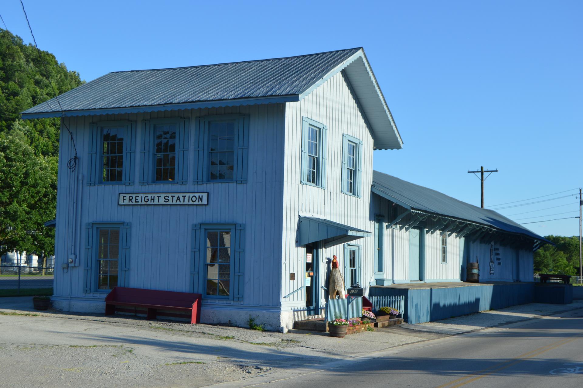 Light blue "Freight Station" building with a long loading dock under clear sky.