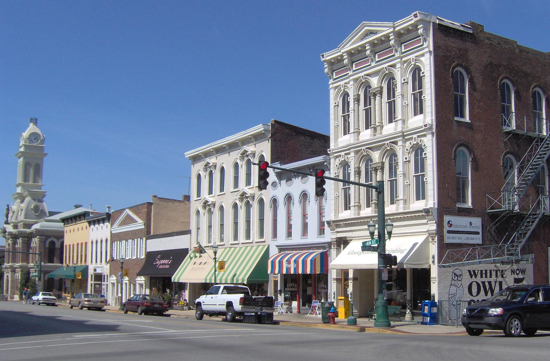Historic downtown street with ornate buildings, cars, and clear blue sky.