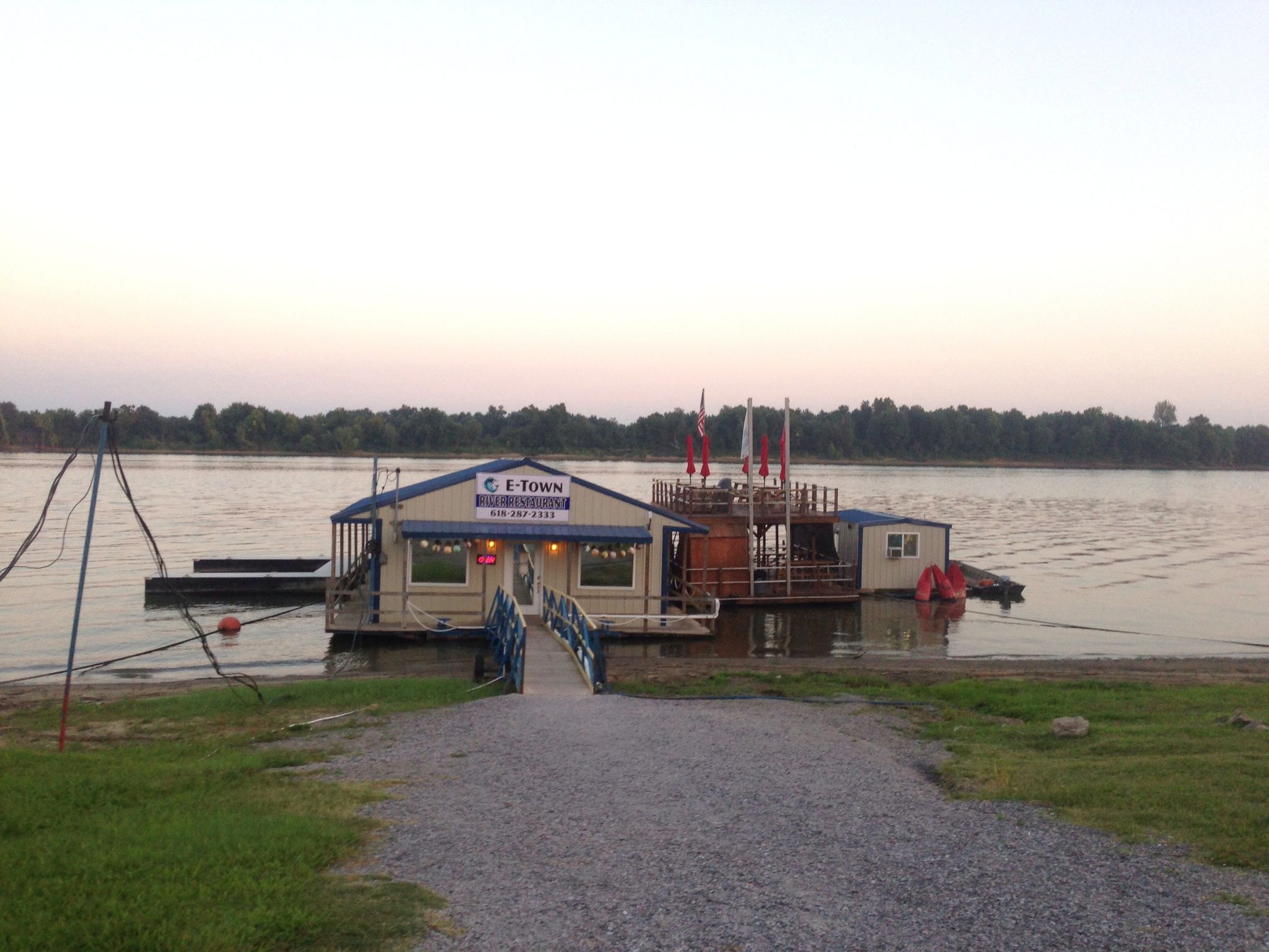 A floating building on a wide river at dusk, with a gravel path. - River to River Trail