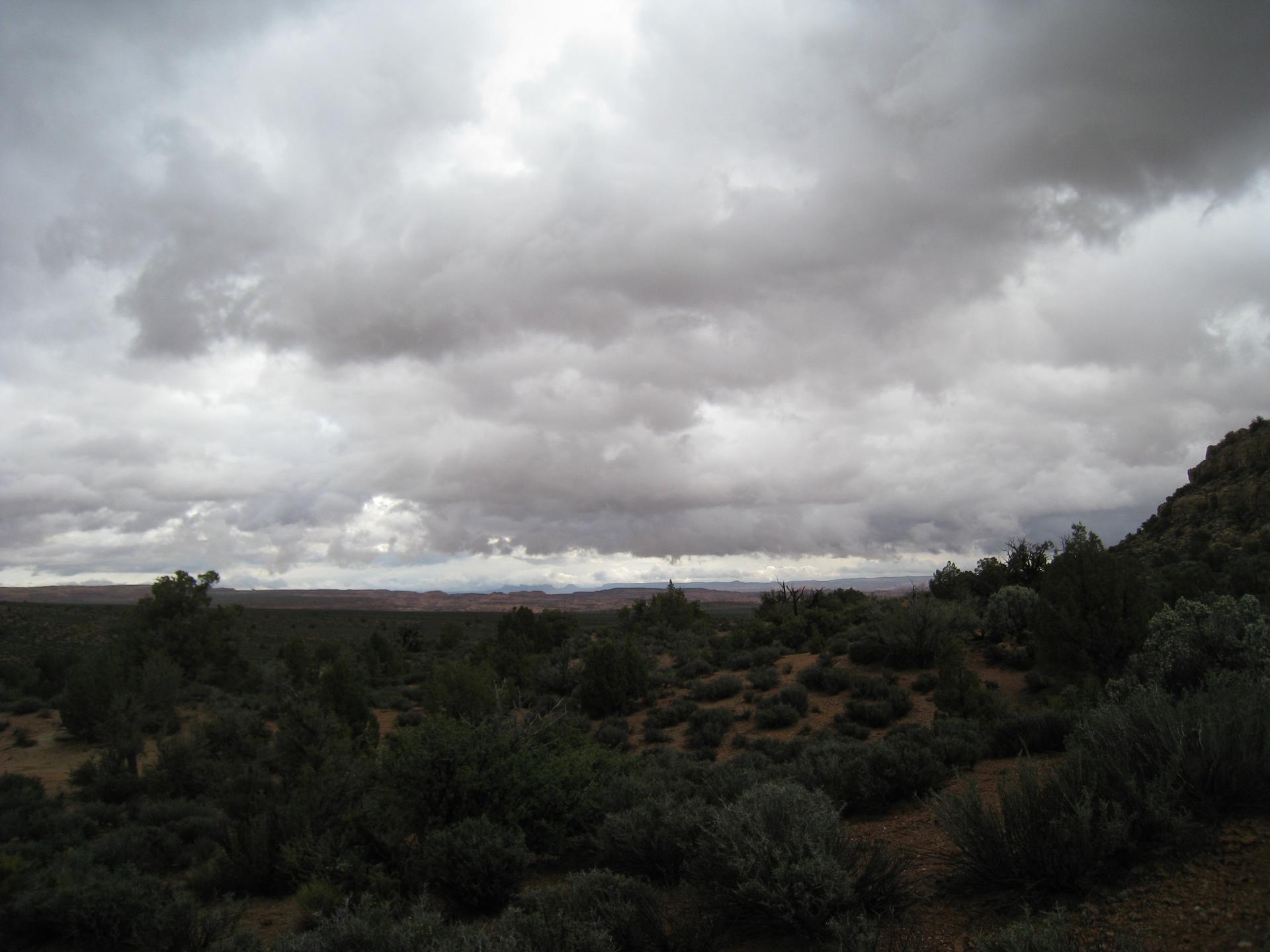 Vast, dark, arid landscape under a dramatic, cloudy sky.