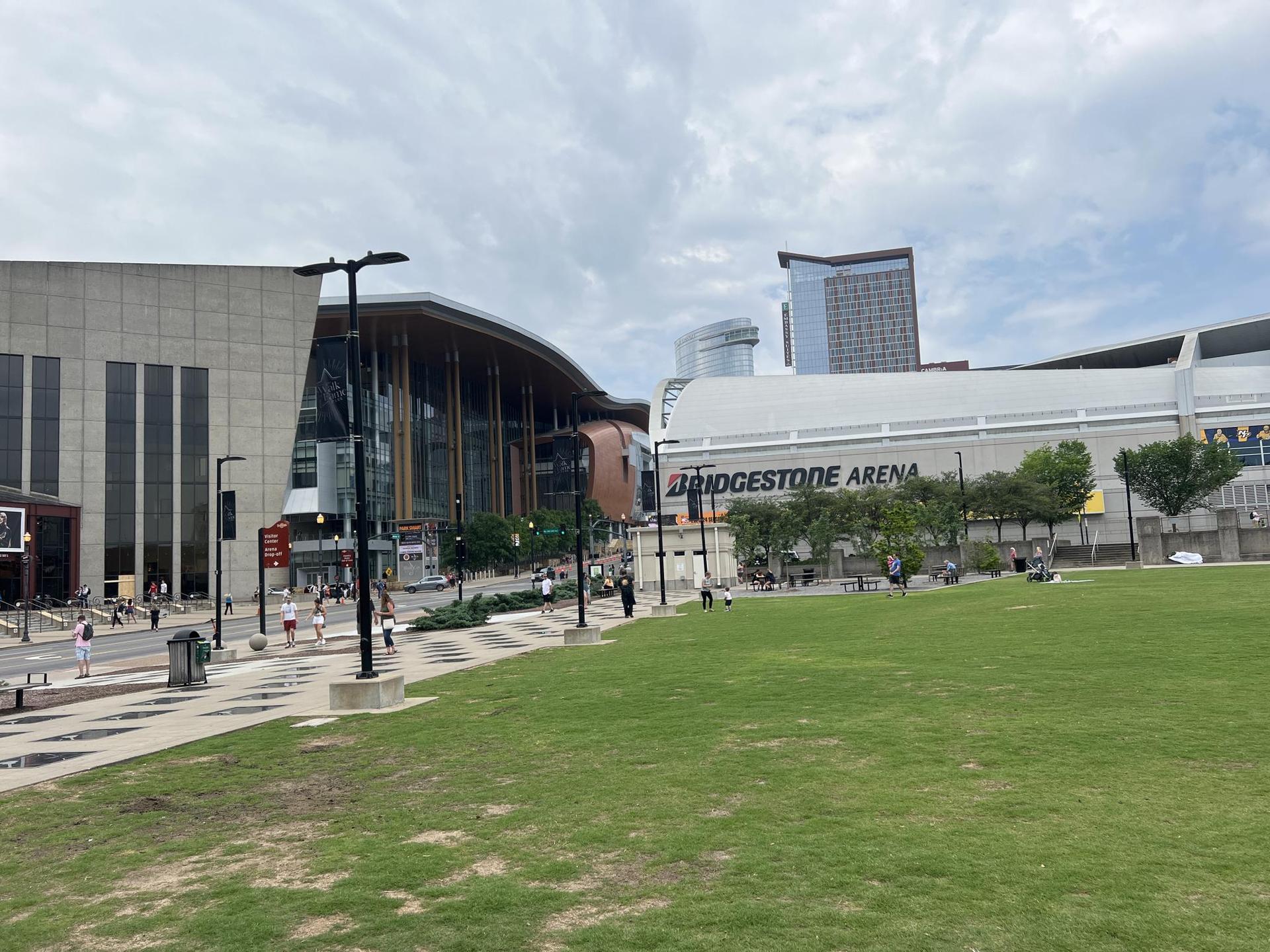 Modern buildings, green lawn, and people walking on a cloudy day.