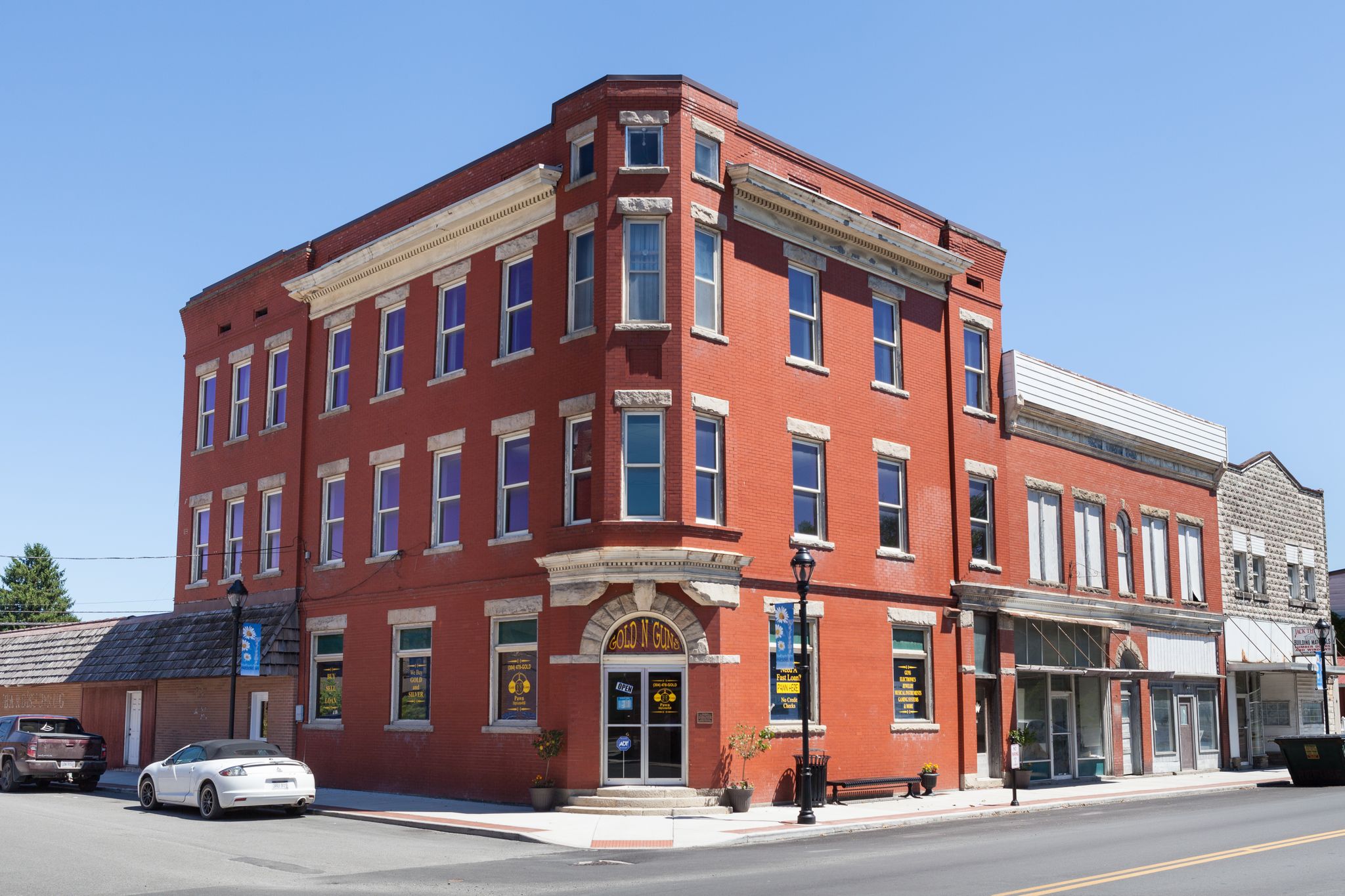 A large red brick building on a sunny street corner with parked cars. - Parsons loop from Thomas