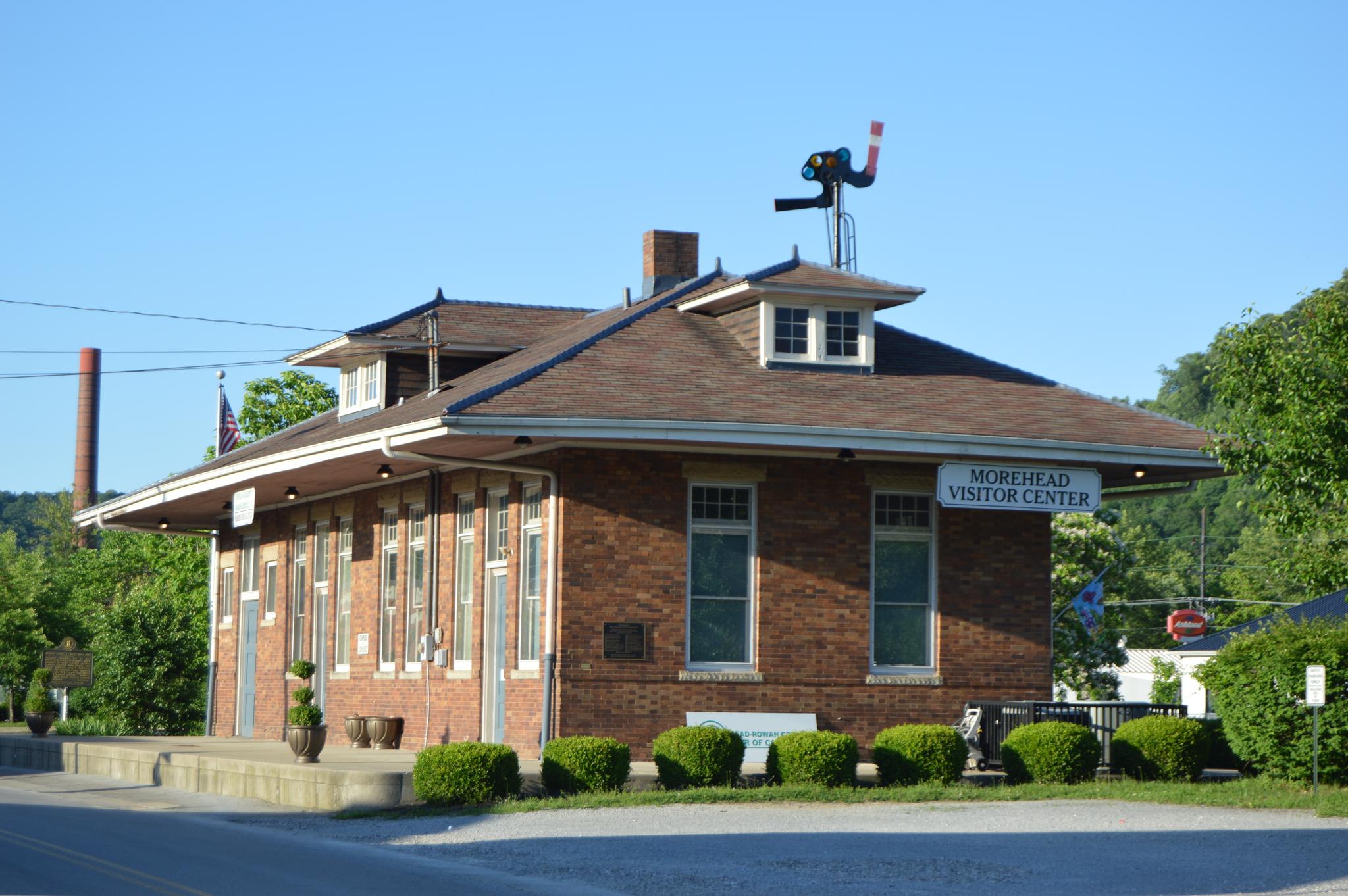 Historic brick building with "Visitor Center" sign under a clear blue sky.