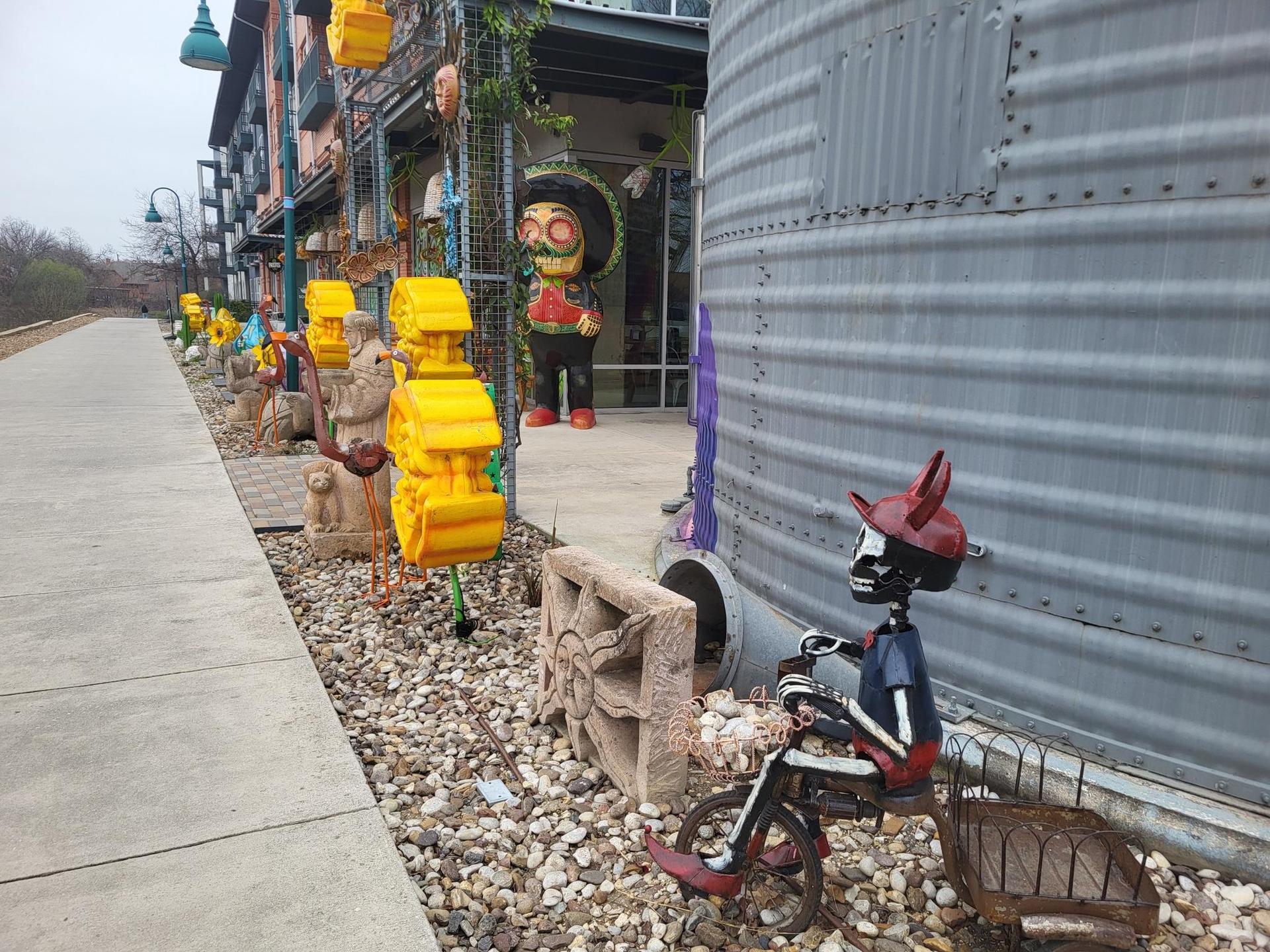 Colorful outdoor art installations line a sidewalk next to a building.