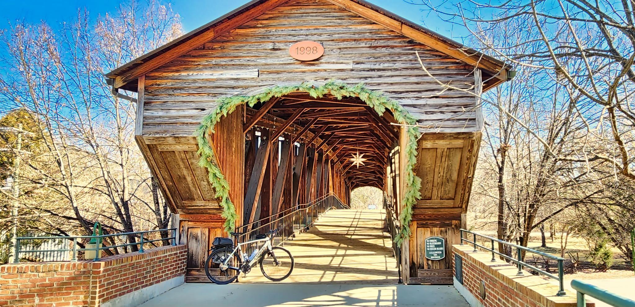 A rustic wooden covered bridge with a bicycle parked at its entrance.