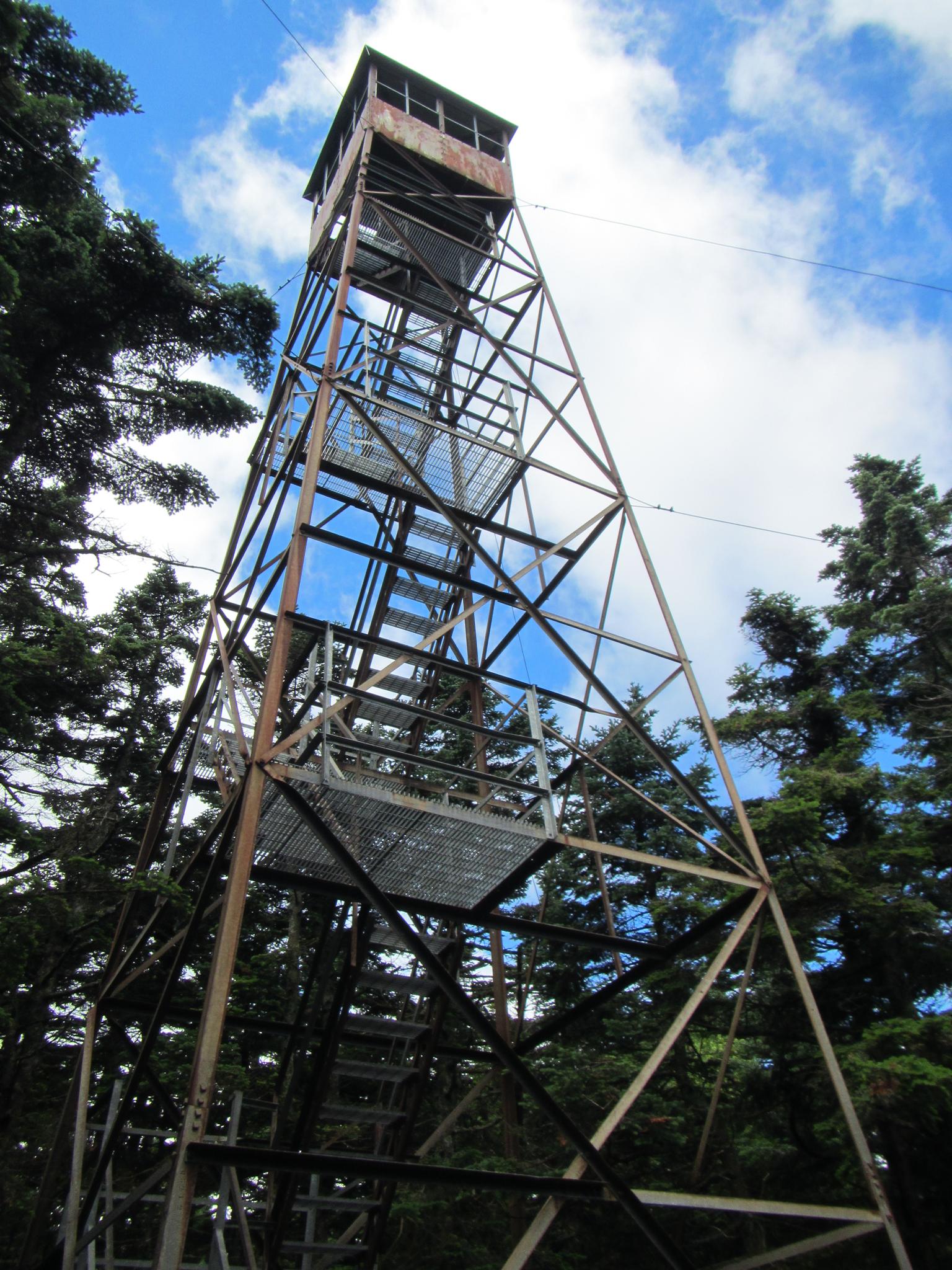 A tall metal fire lookout tower stands against a bright blue sky.