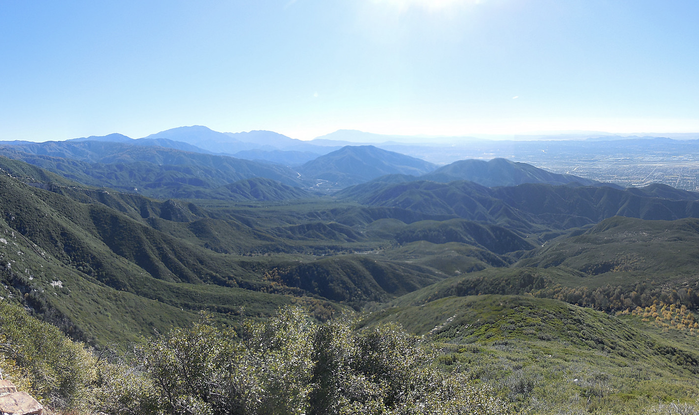 Expansive view of green, forested mountains and valleys under a bright, sunny sky. - Monument Peak via Bailey Canyon Road