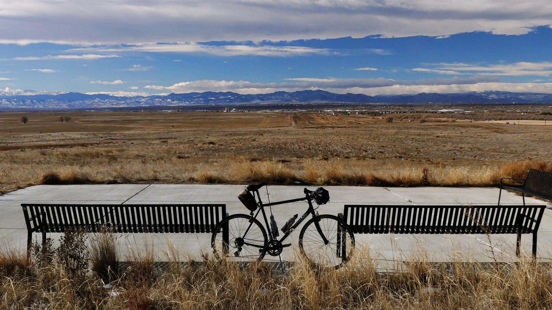 A bicycle rests between two benches overlooking a vast, dry landscape.