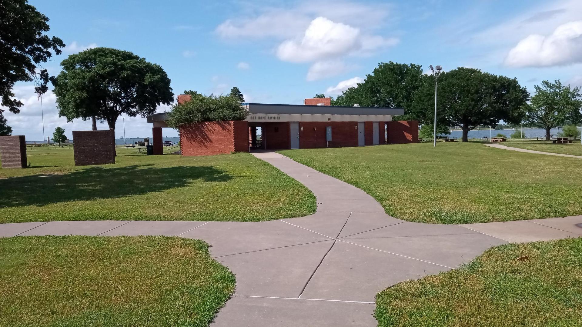 Paved paths lead to a brick building in a grassy park setting.