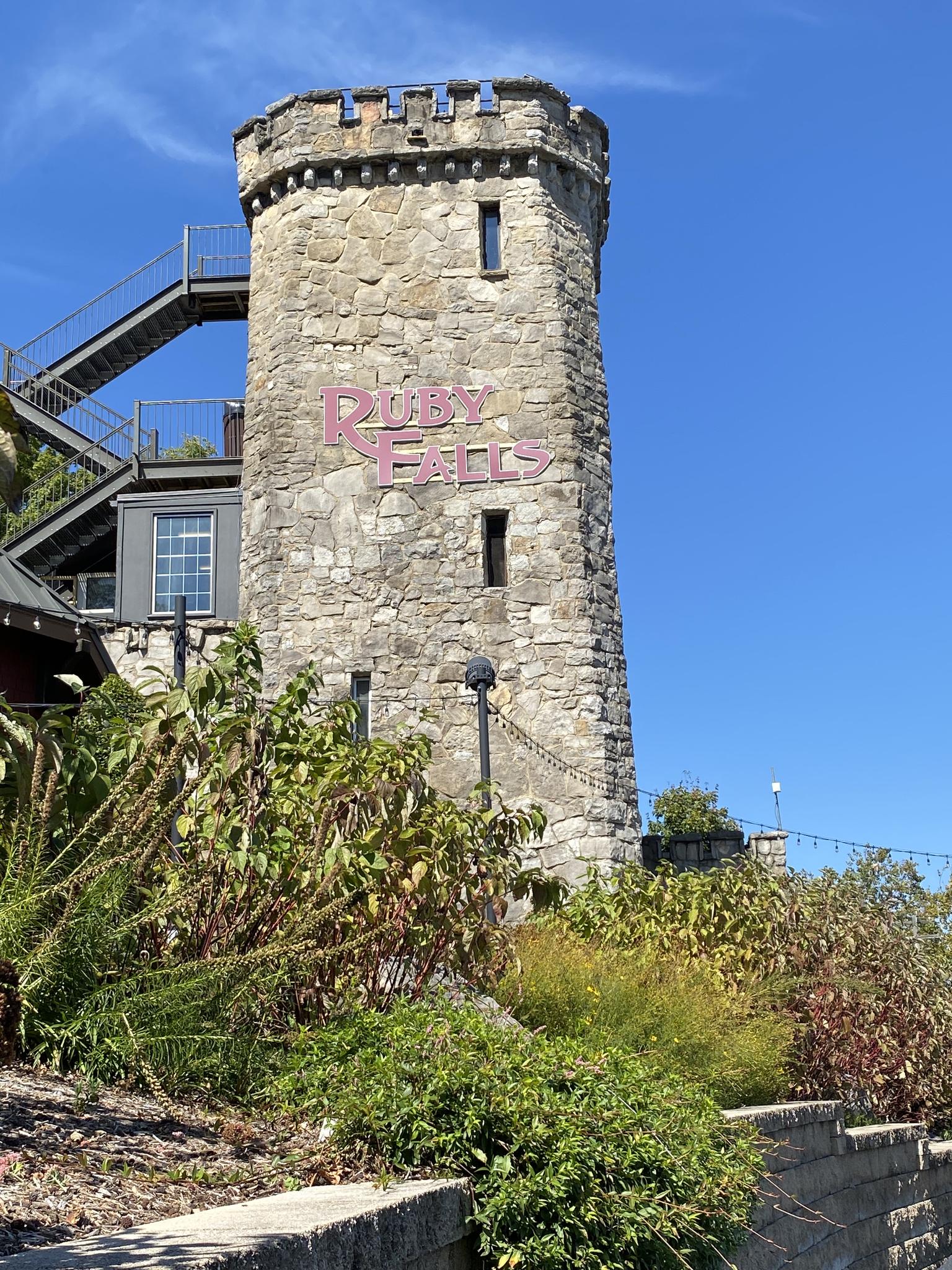 A tall, medieval-style stone tower stands against a clear blue sky.