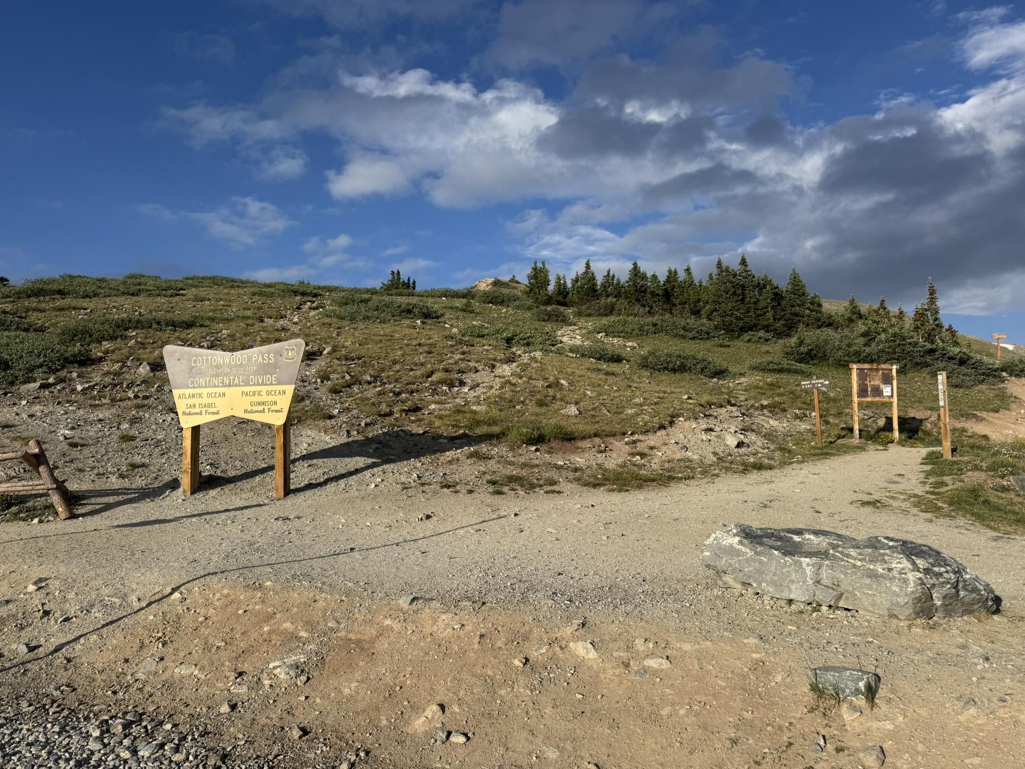 Two wooden signs on a dirt path leading up a grassy hill. - Cottonwood Pass from Buena Vista