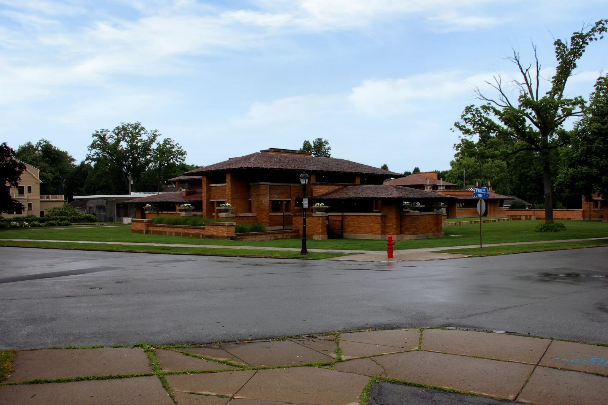 A large, low-slung brick building at a wet street intersection.