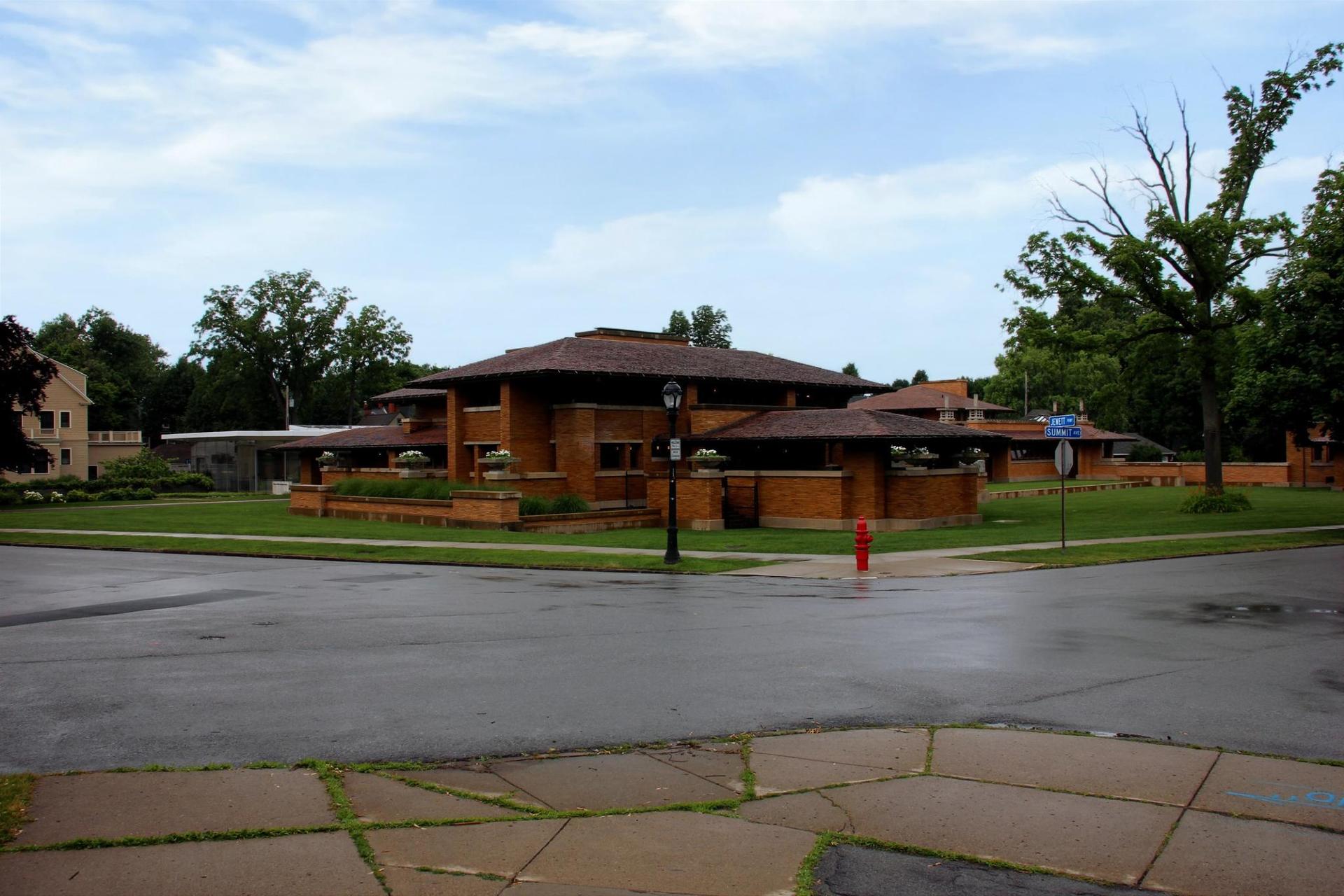 A large, low-slung brick building at a wet street intersection.