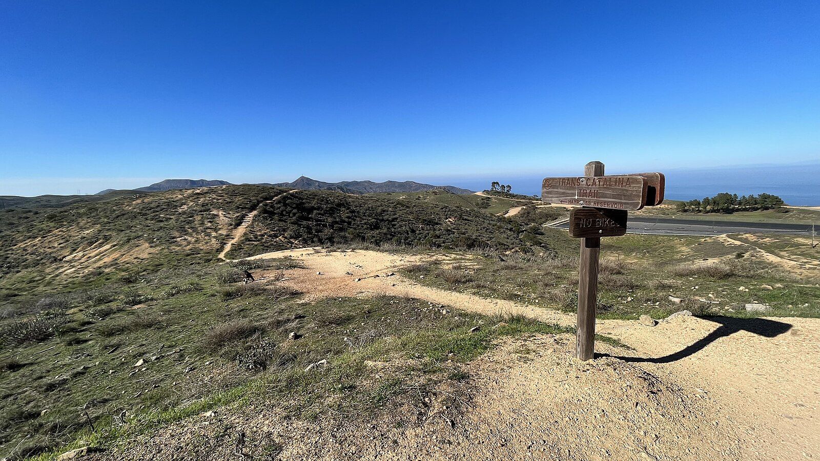 Wooden trail sign on a hilltop overlooking green hills and distant ocean. - Hermit Gulch Campground – Trail marker & viewpoint loop from Avalon