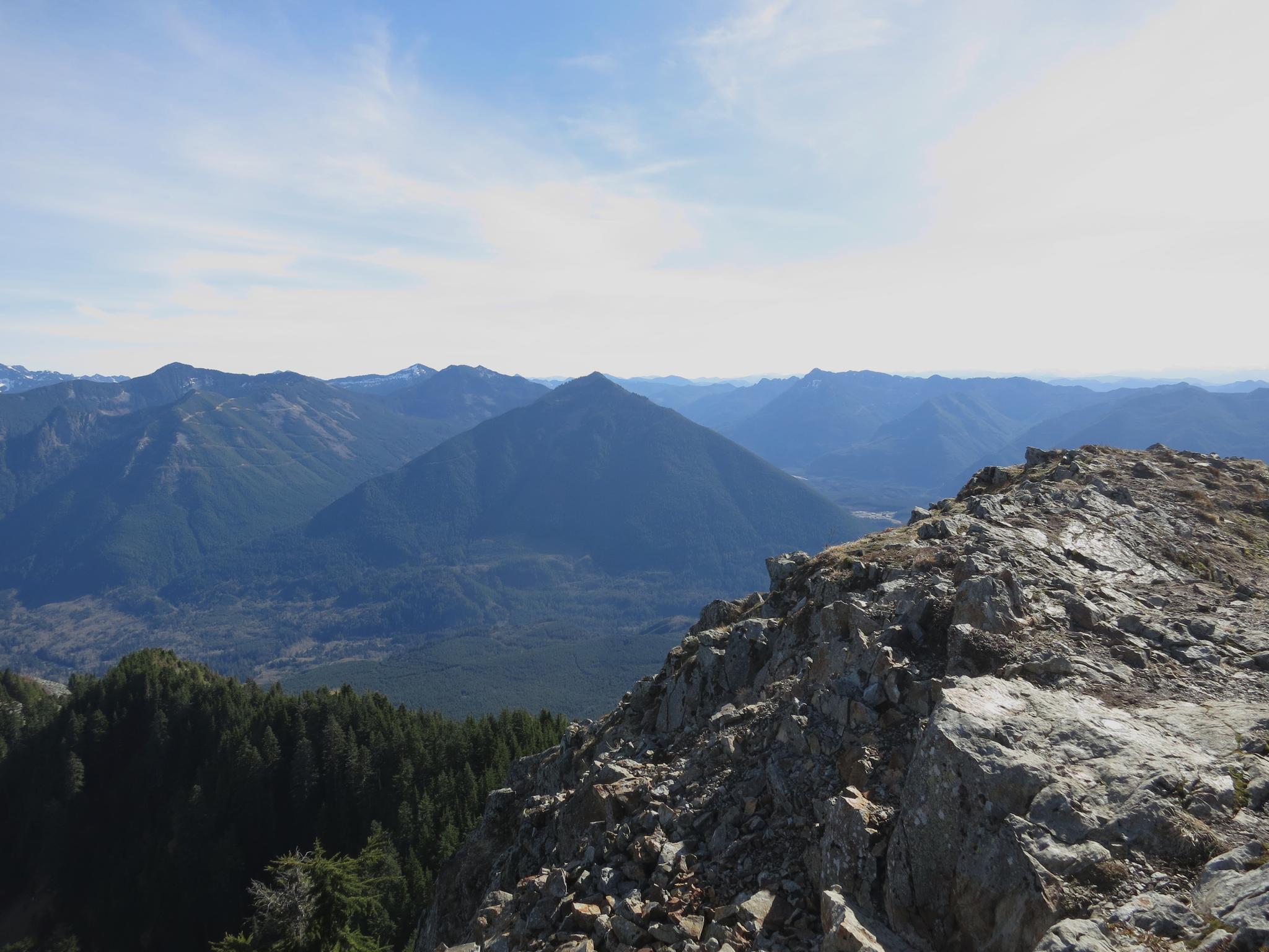Panoramic view of distant mountains and valleys from a rocky peak.