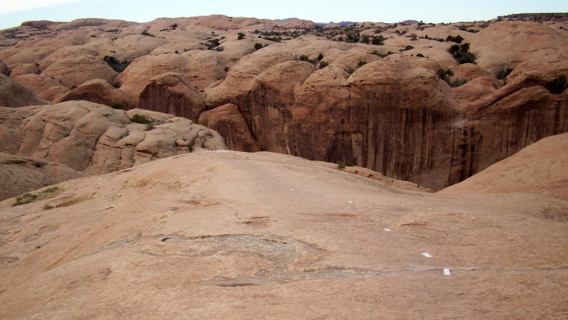 Expansive red rock landscape with deep canyons under a bright sky.