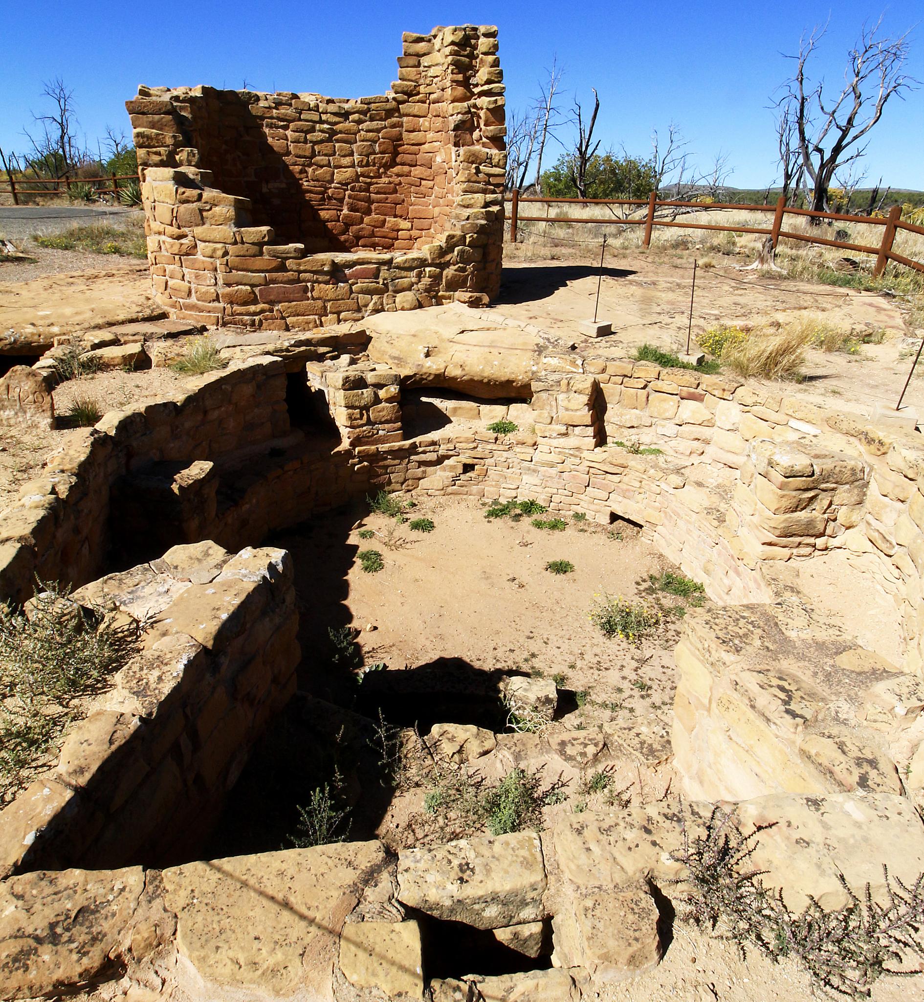 Ancient stone ruins with excavated areas under a bright blue sky.