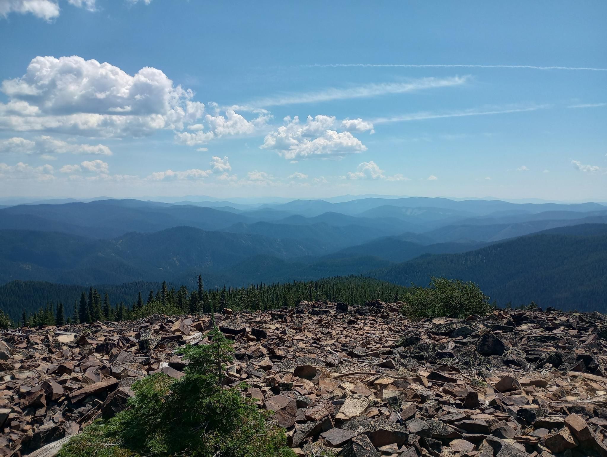 Vast mountain range under a bright blue sky with rocky foreground. - South Chilco Mountain Trail