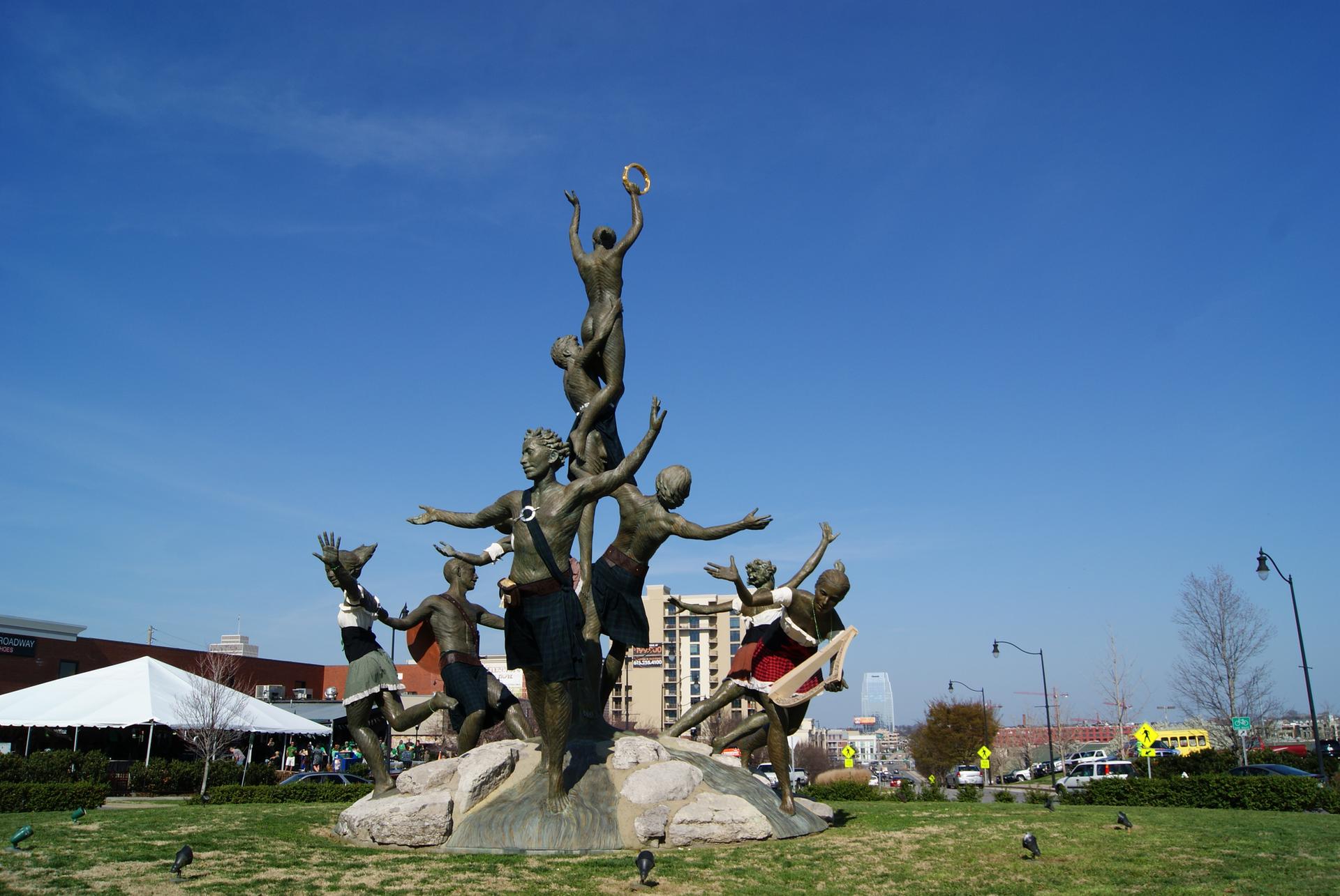 Large bronze statue of multiple figures under a clear blue sky.