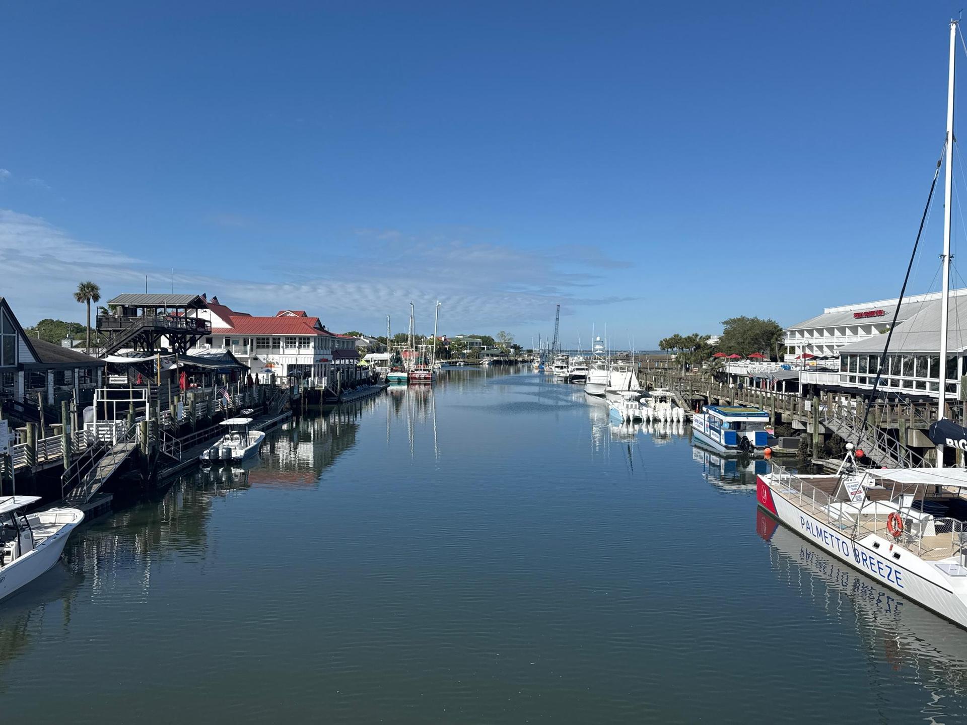 Boats docked along a narrow waterway lined with buildings on a sunny day.