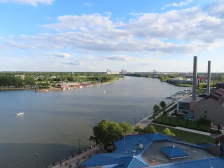 Aerial view of a wide river flowing through a city under a cloudy sky.