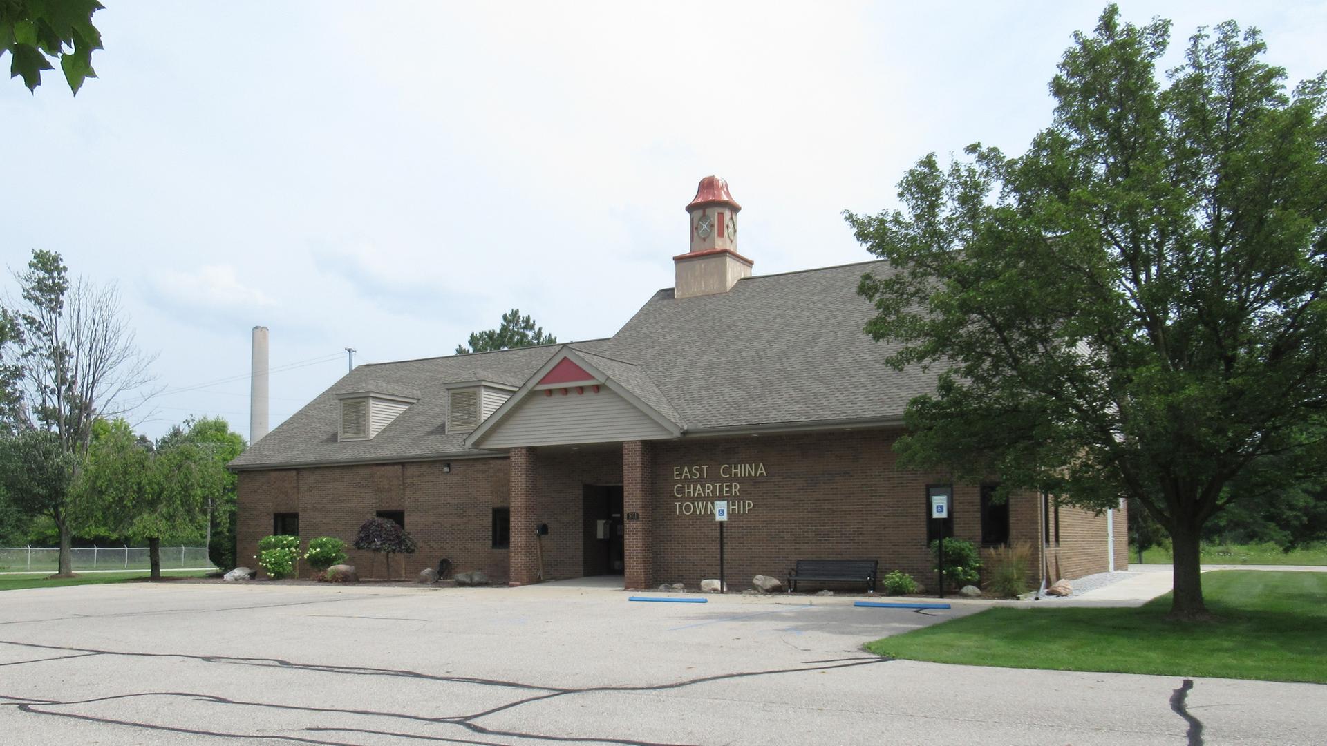 Brick building with a red cupola, surrounded by trees and a parking lot.