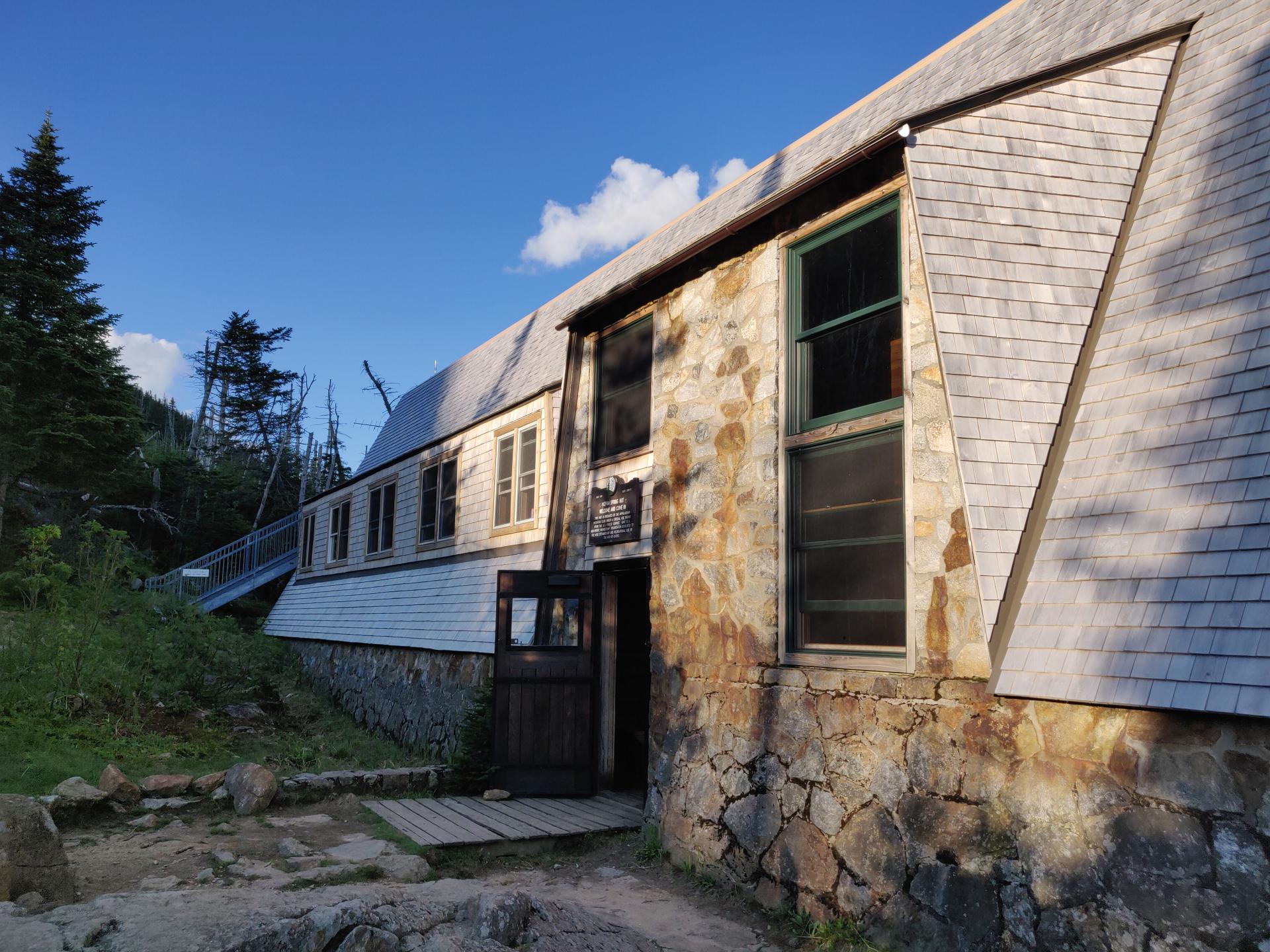 A rustic stone and wood building under a clear, sunny sky.