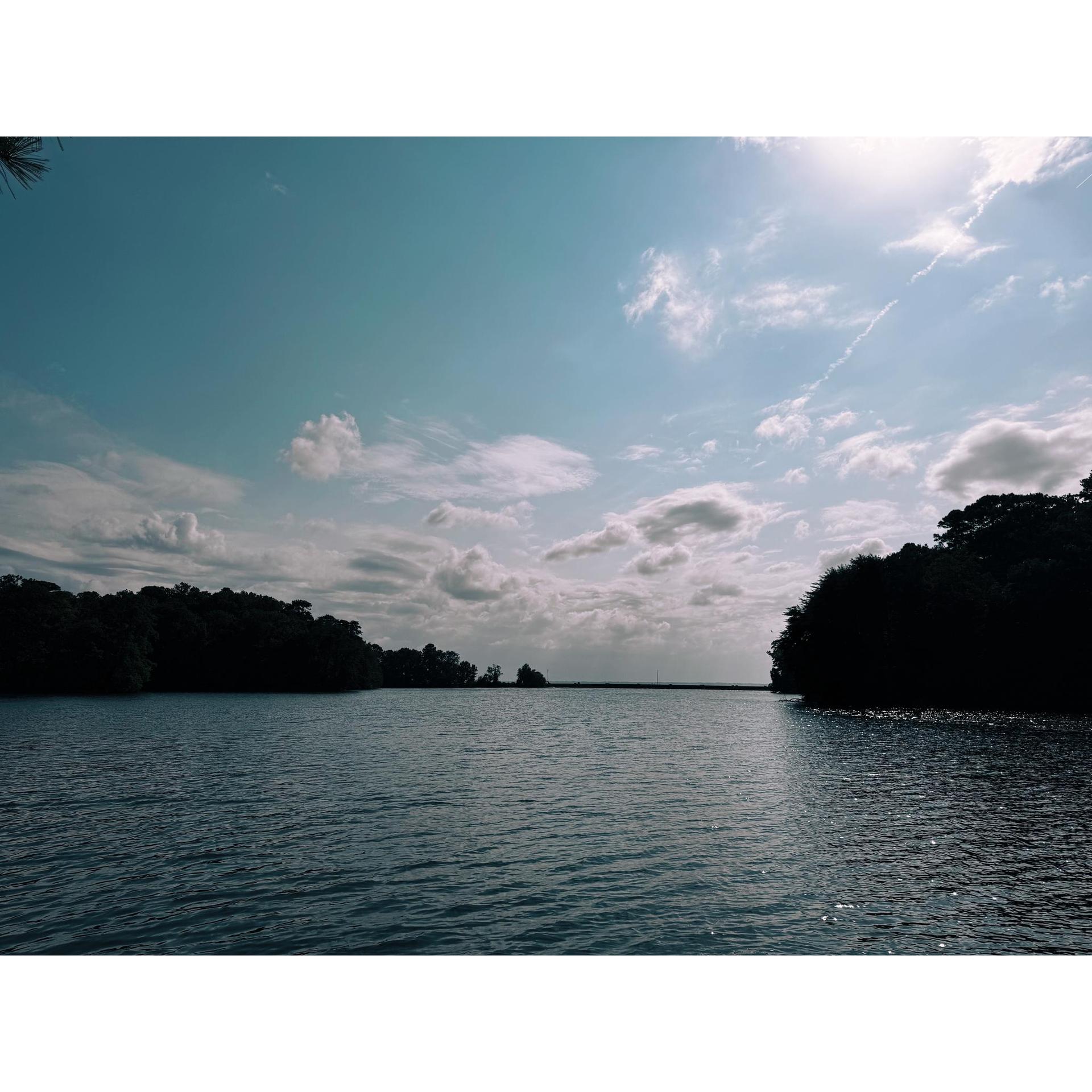 Wide body of water under a bright, partly cloudy sky.
