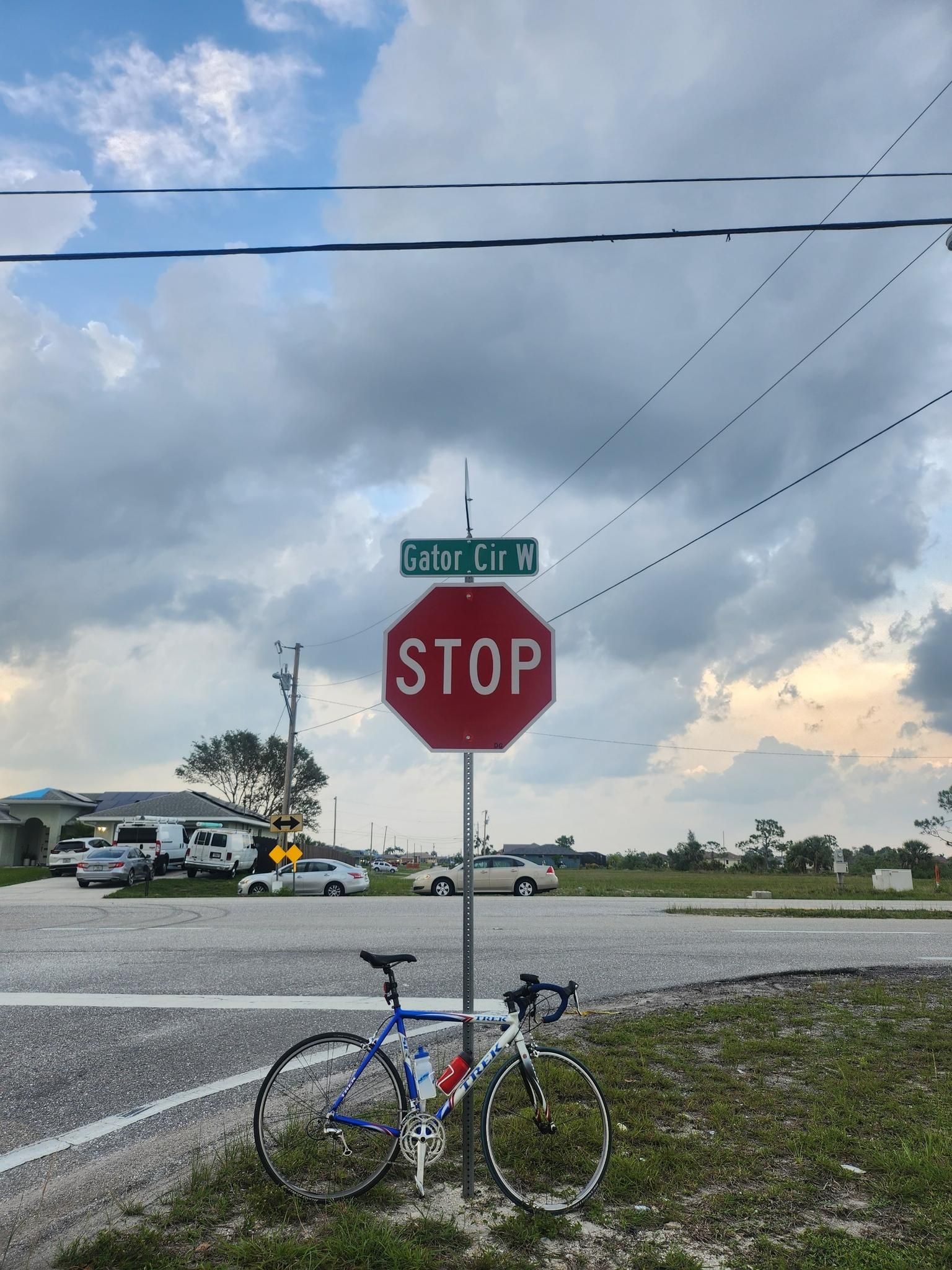 Bicycle parked by a stop sign at a street intersection under an overcast sky. - Gator Trails loop