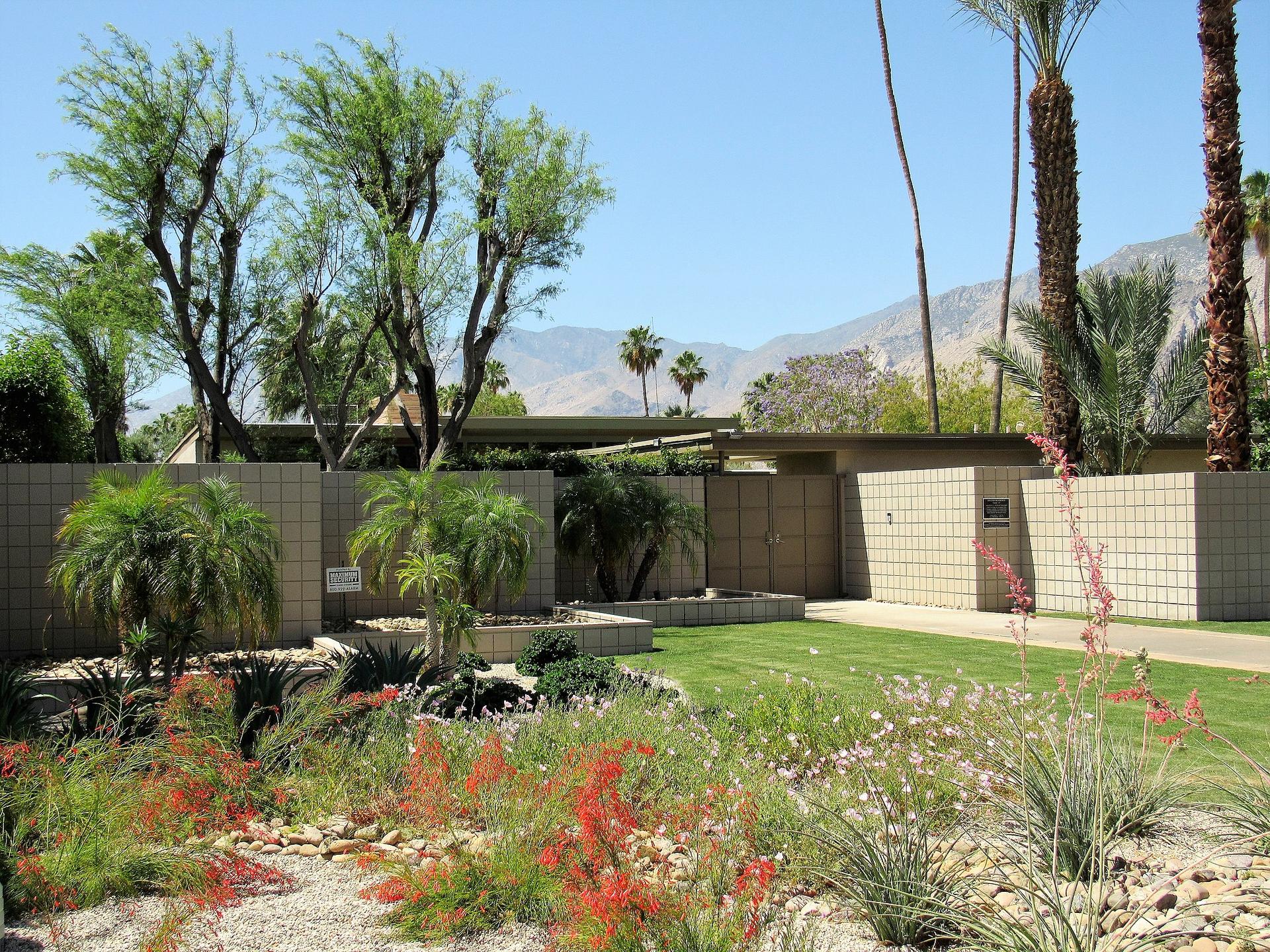 Modern building with landscaped garden, desert plants, and distant mountains.