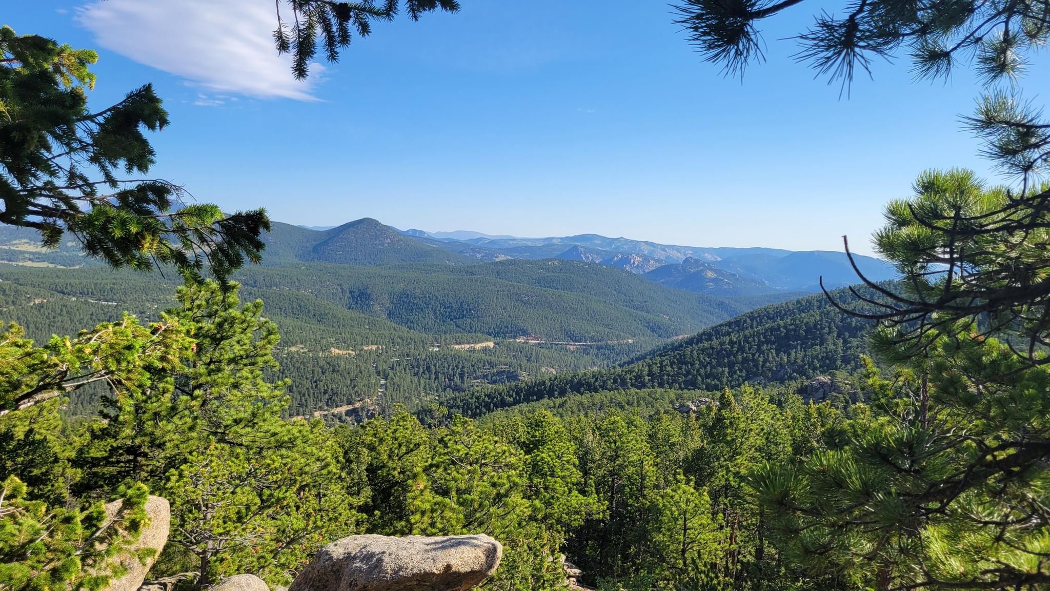 A panoramic view of rolling forested mountains under a clear blue sky. - Miller Rock OHV Trail