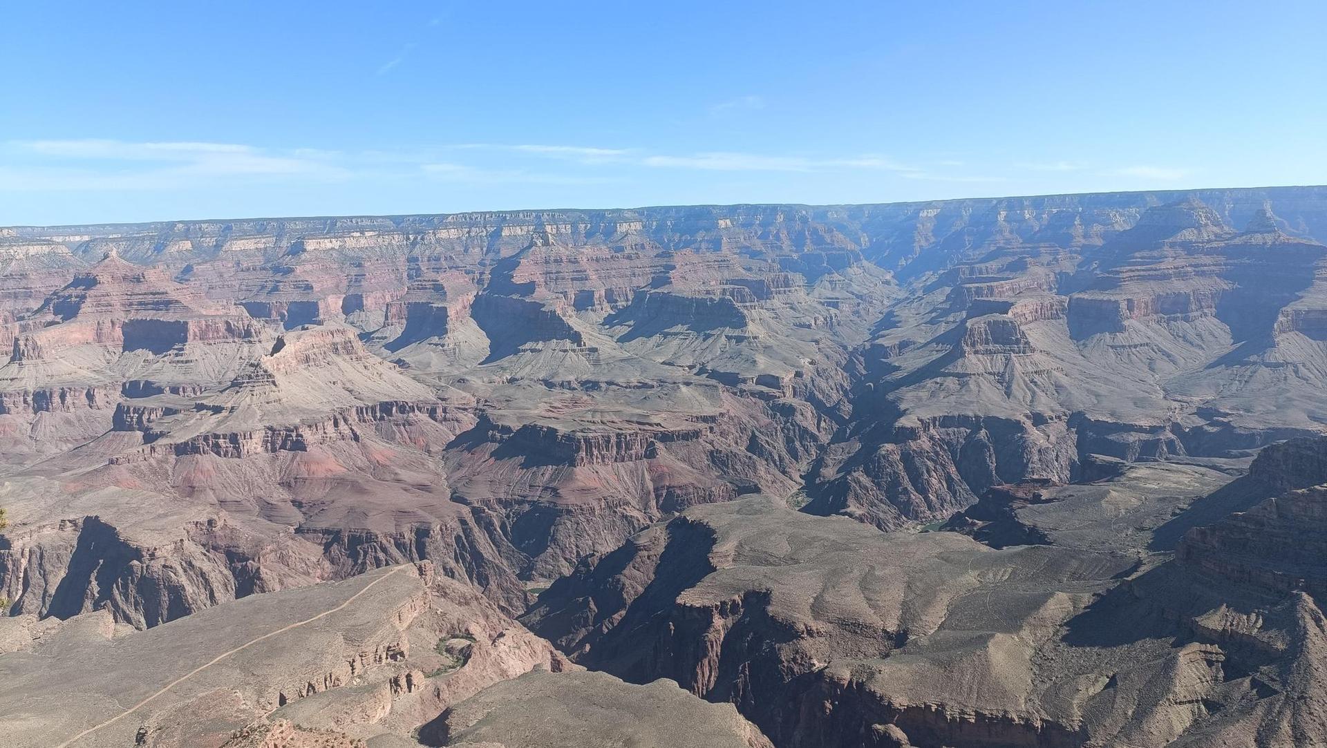 Vast, arid canyon landscape with numerous layered rock formations under a clear sky.