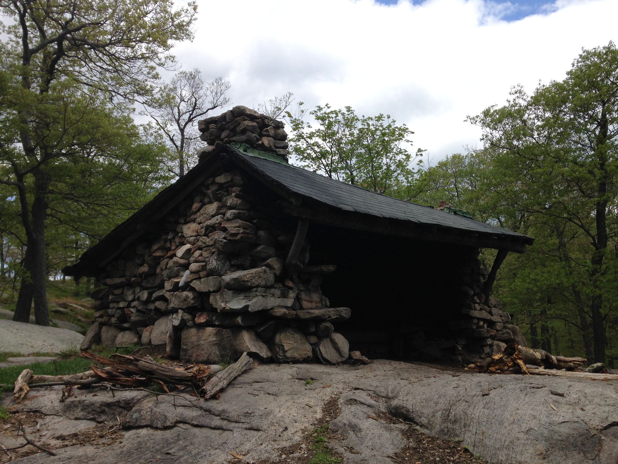 Rustic stone lean-to on a rock, surrounded by green trees under an overcast sky. - Fingerboard Mountain via Appalachian Trail and Long Path Loop