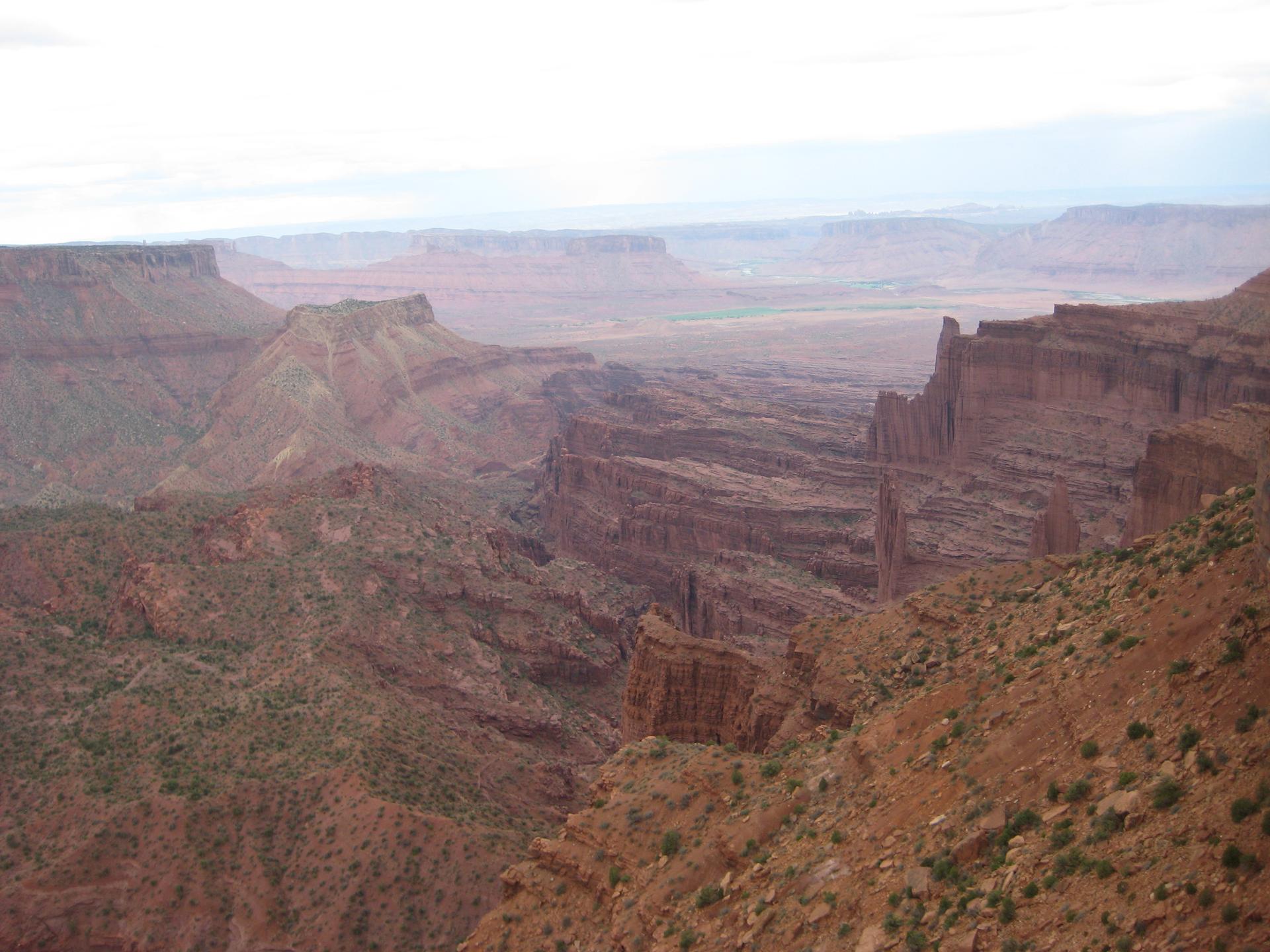 Expansive view of deep red rock canyons and mesas under a hazy sky.