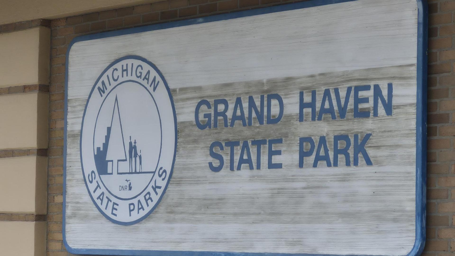 A weathered sign with text and a state park logo on a building.