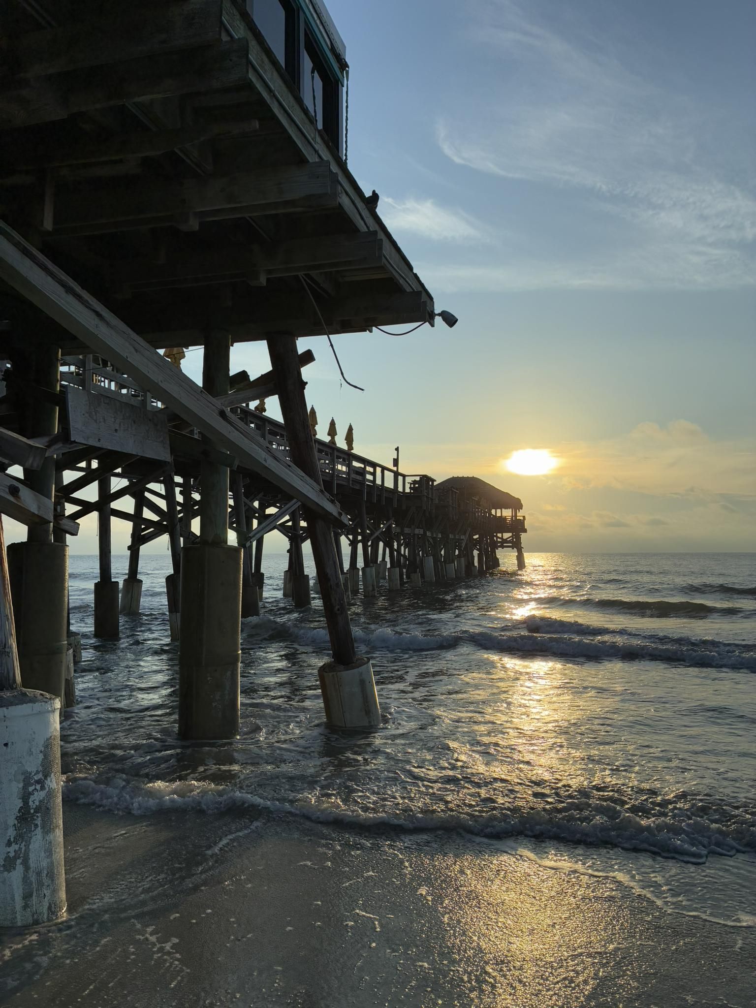 Pier over ocean at sunrise, with waves crashing near the structure. - Cocoa Beach Pier – Beautiful wooden boardwalk parallel to the sea loop from Hail Island