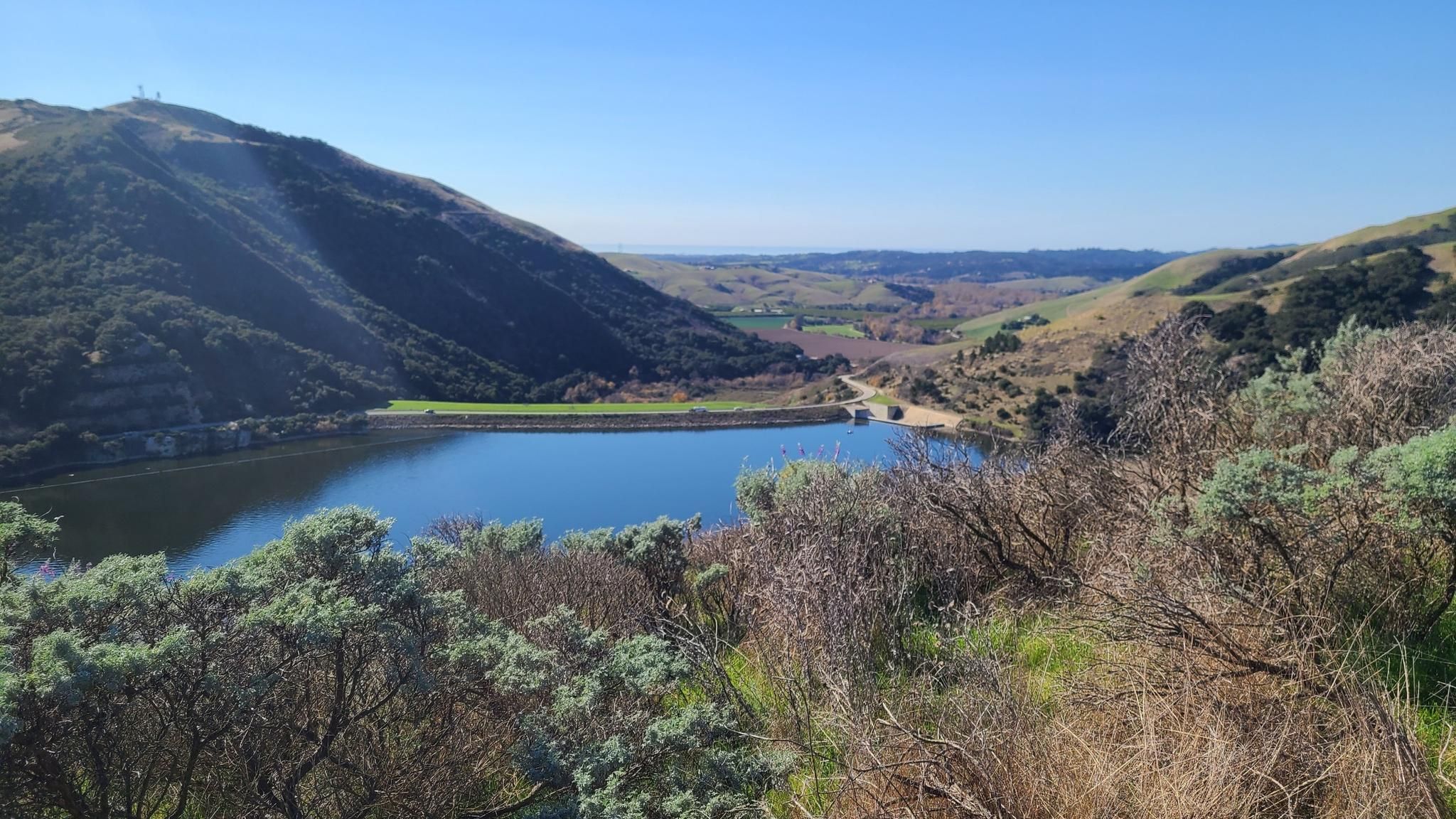 Blue lake nestled between green and golden hills under a bright sky. - Lopez Lake Recreation Area loop