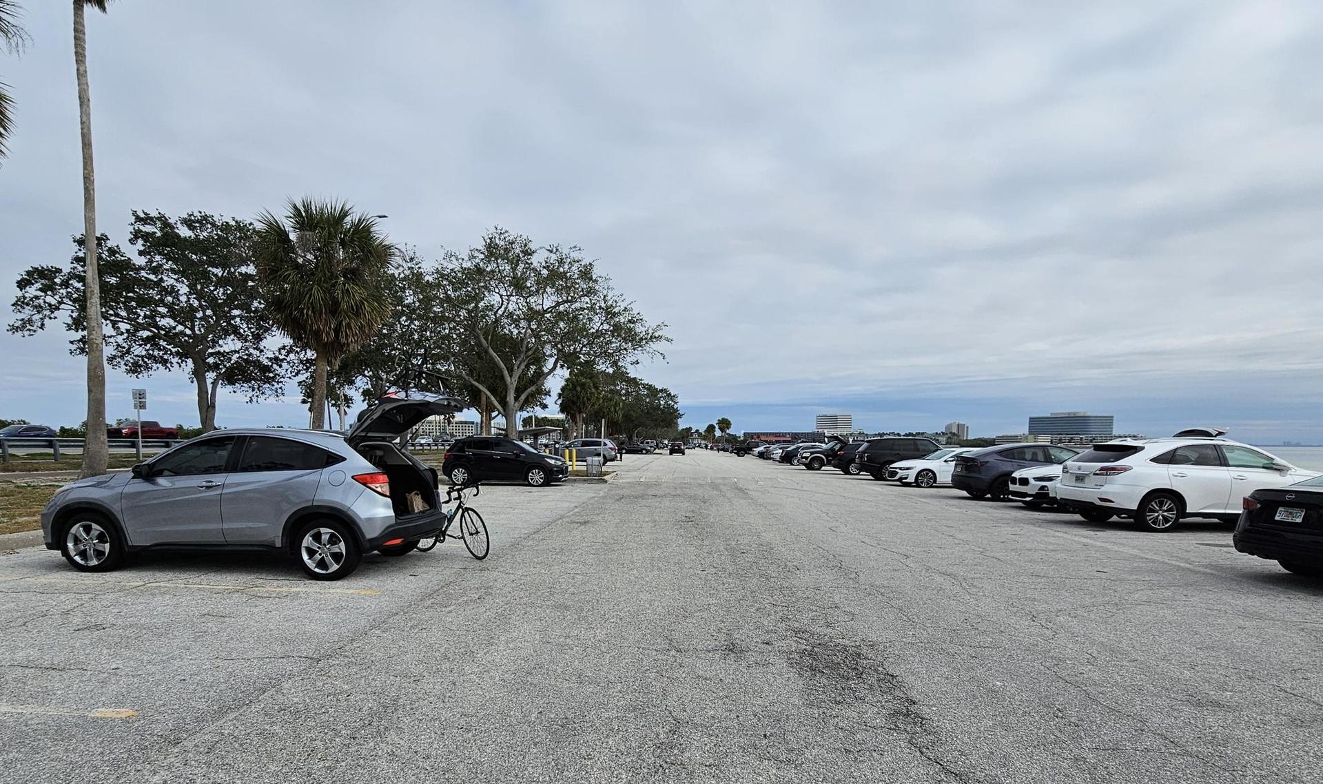 Parking lot filled with cars and a bicycle under an overcast sky.