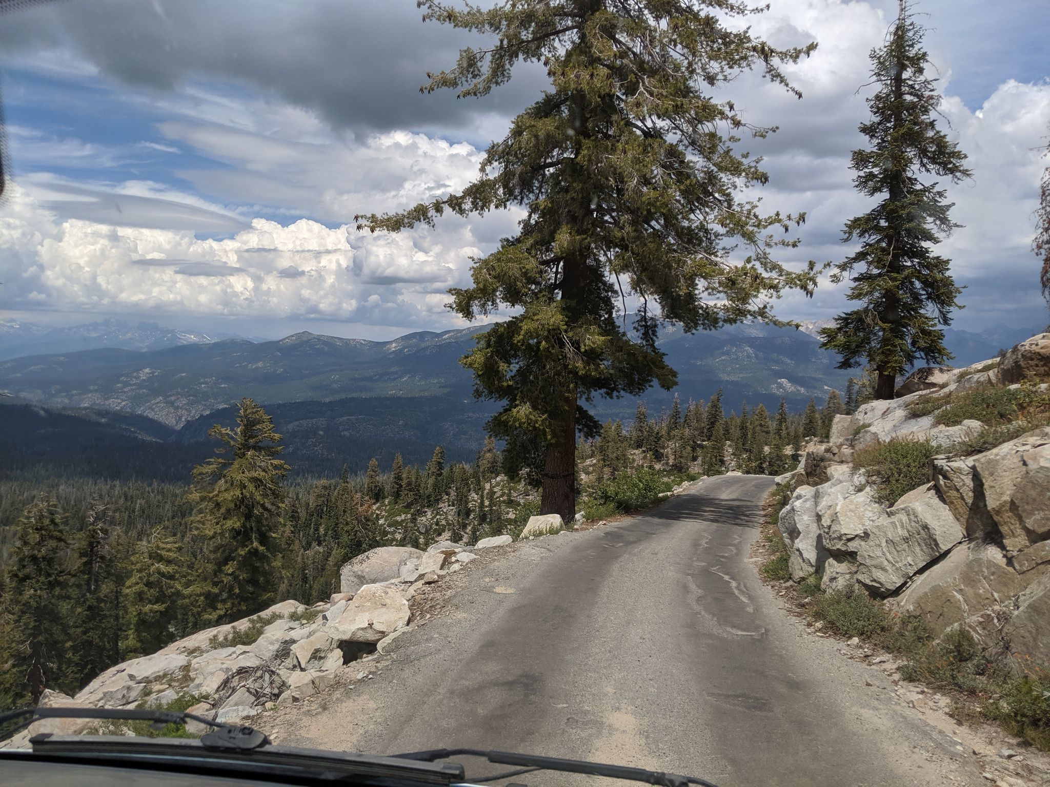 Mountain road winding through rocky terrain with pine trees under cloudy sky. - Kaiser Peak loop