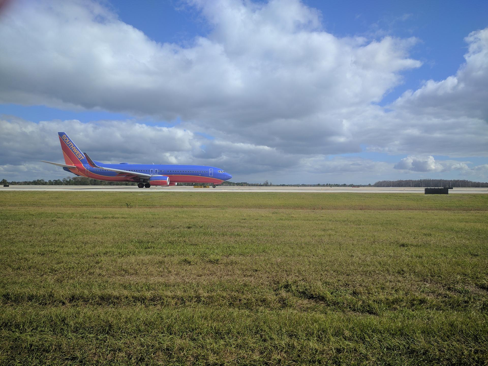 A large blue and red airplane on a runway under a bright, cloudy sky.