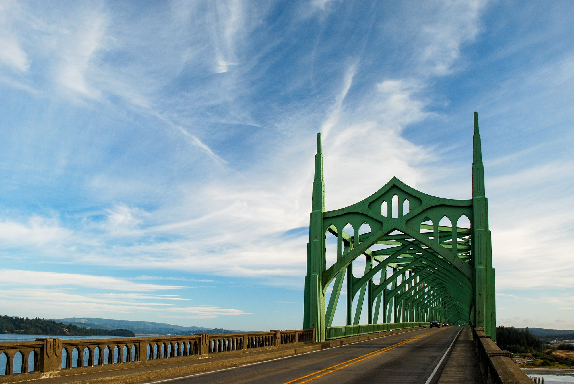Ornate green arched bridge over water under a dramatic cloudy sky. - Oregon Coast Scenic Bikeway: Coos Bay Loop