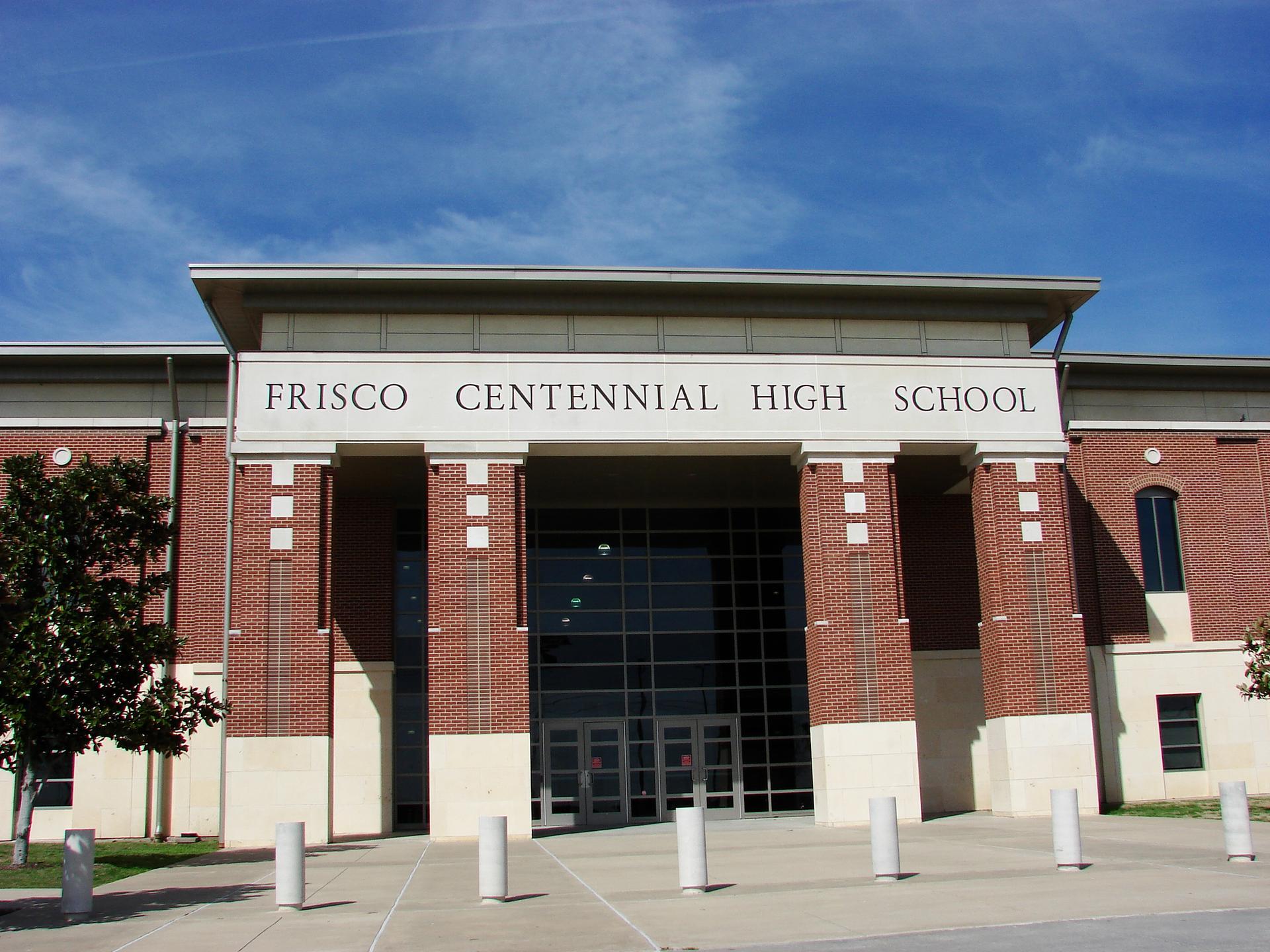 Large brick building entrance with columns under a bright blue sky.