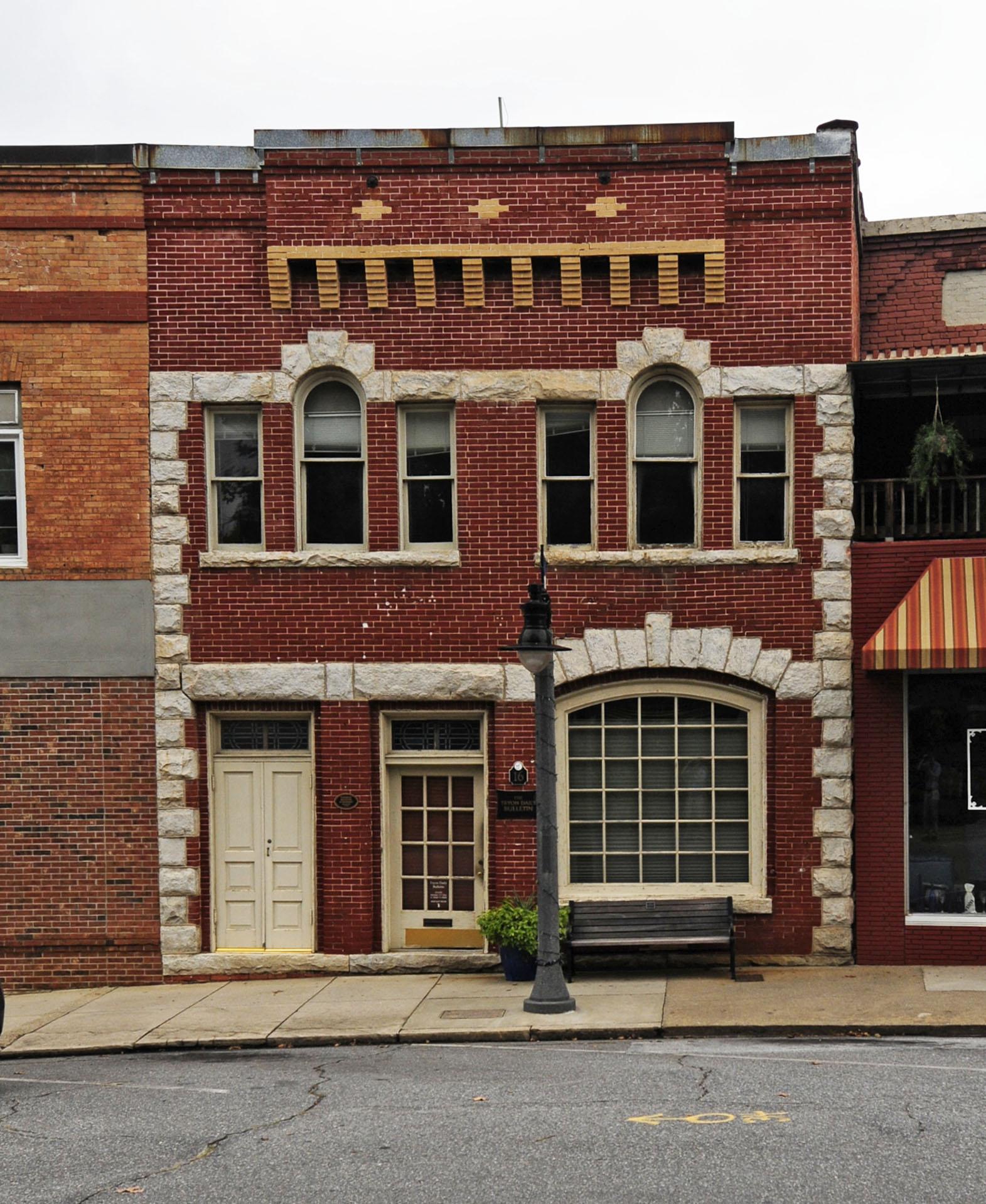 A red brick building with stone trim and two doors under overcast daylight.