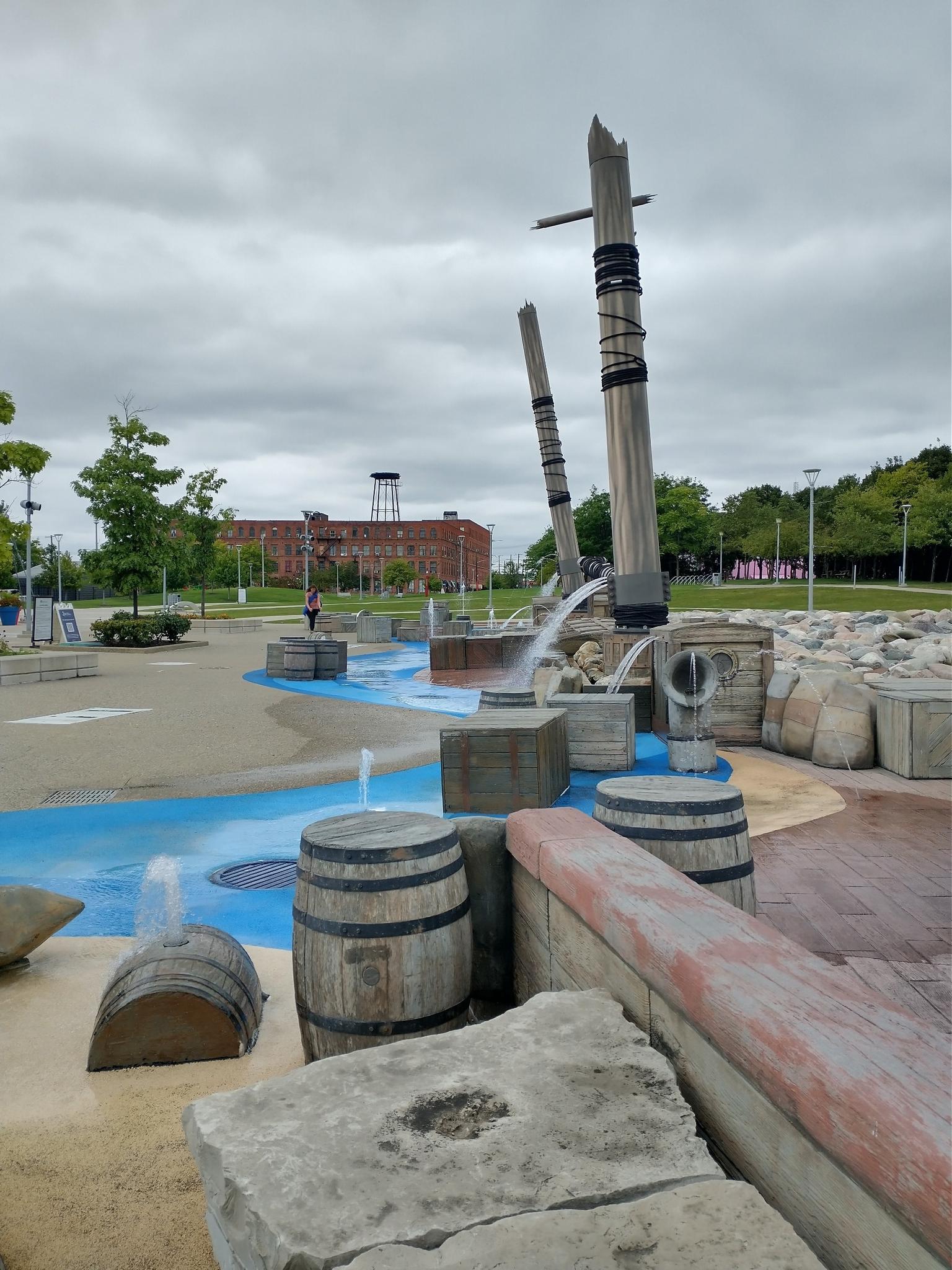 Water play area with wooden barrels and posts under an overcast sky.