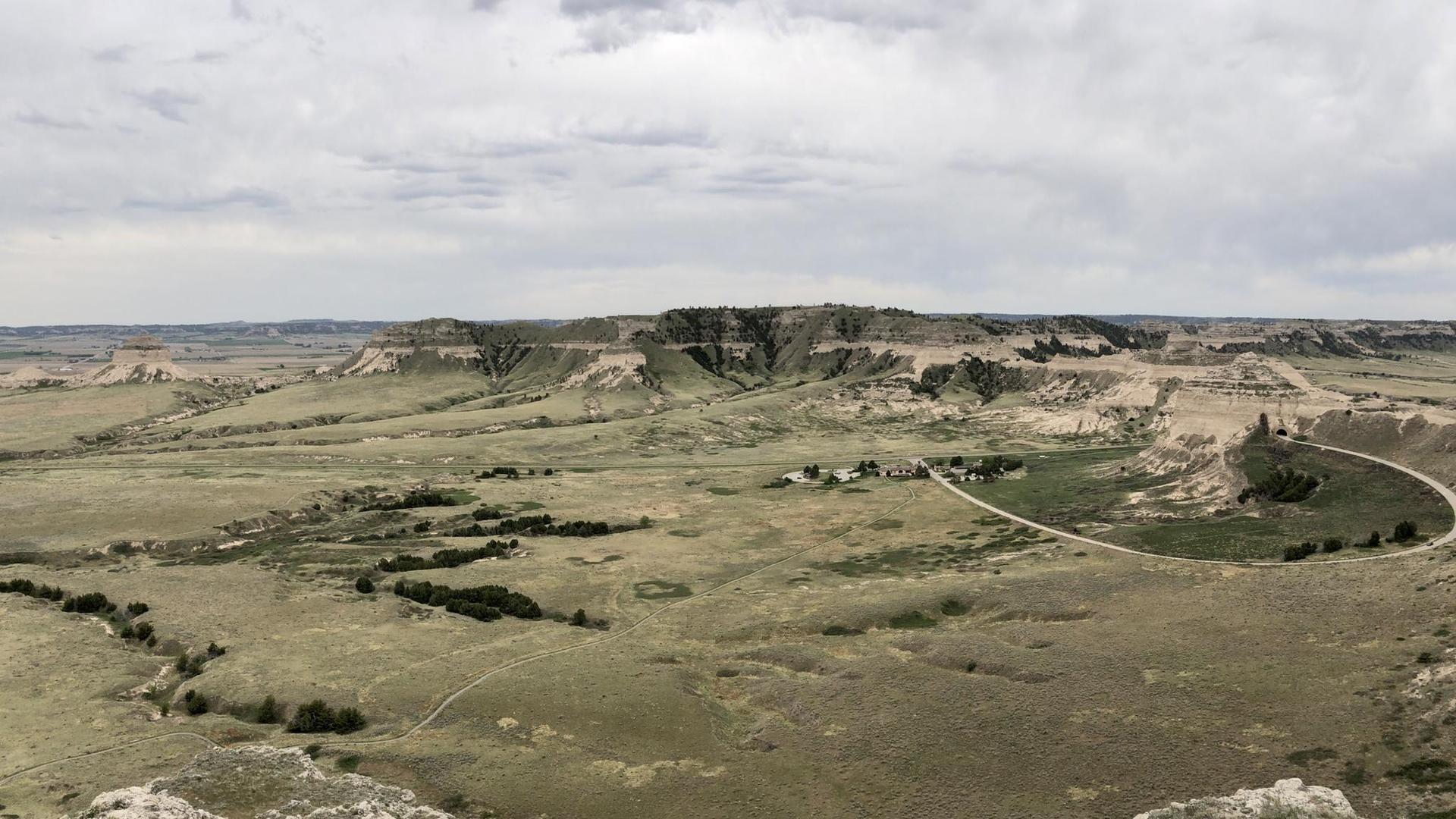 Vast, flat, grassy plains with distant cliffs and a winding road.