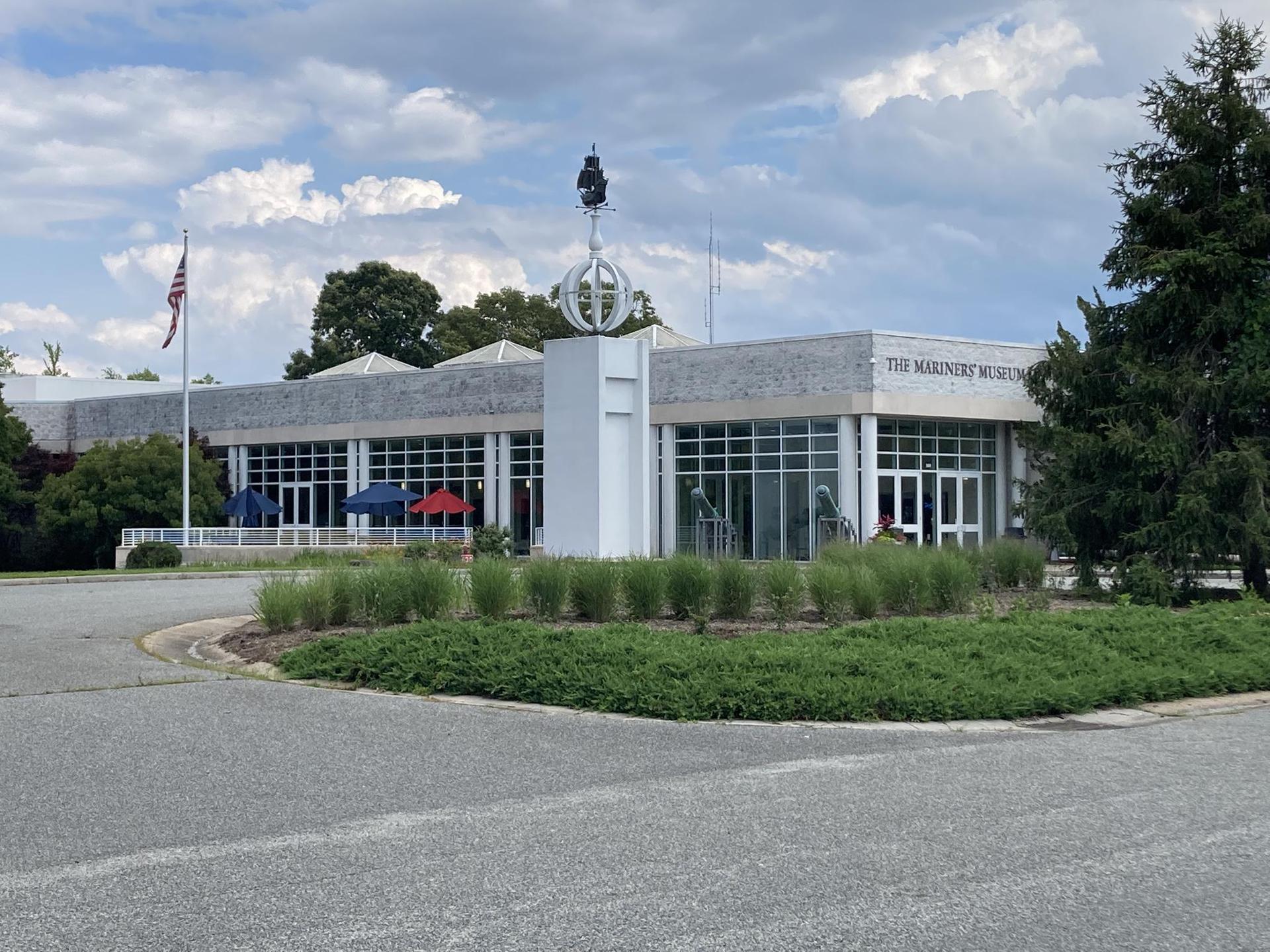 Modern building with large windows, flagpole, and a decorative sculpture outside.