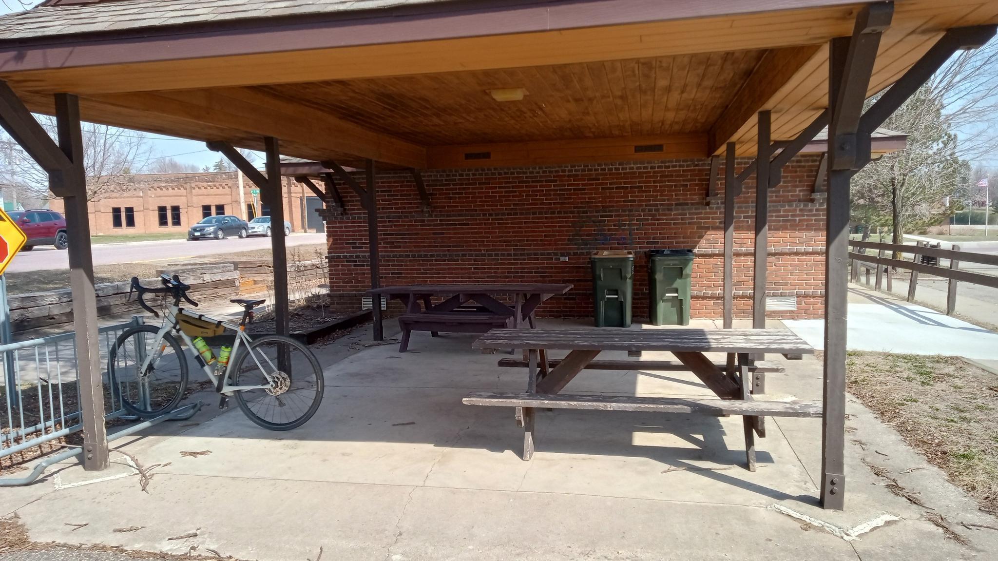 Covered picnic area with tables and a bicycle parked nearby.