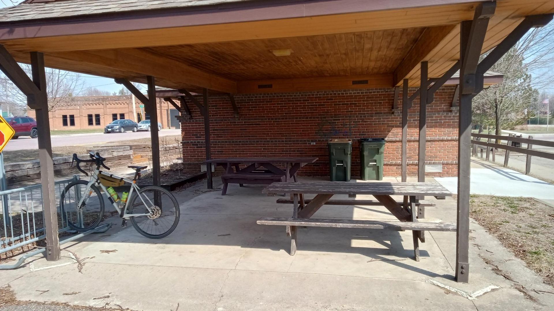 Covered picnic area with tables and a bicycle parked nearby.