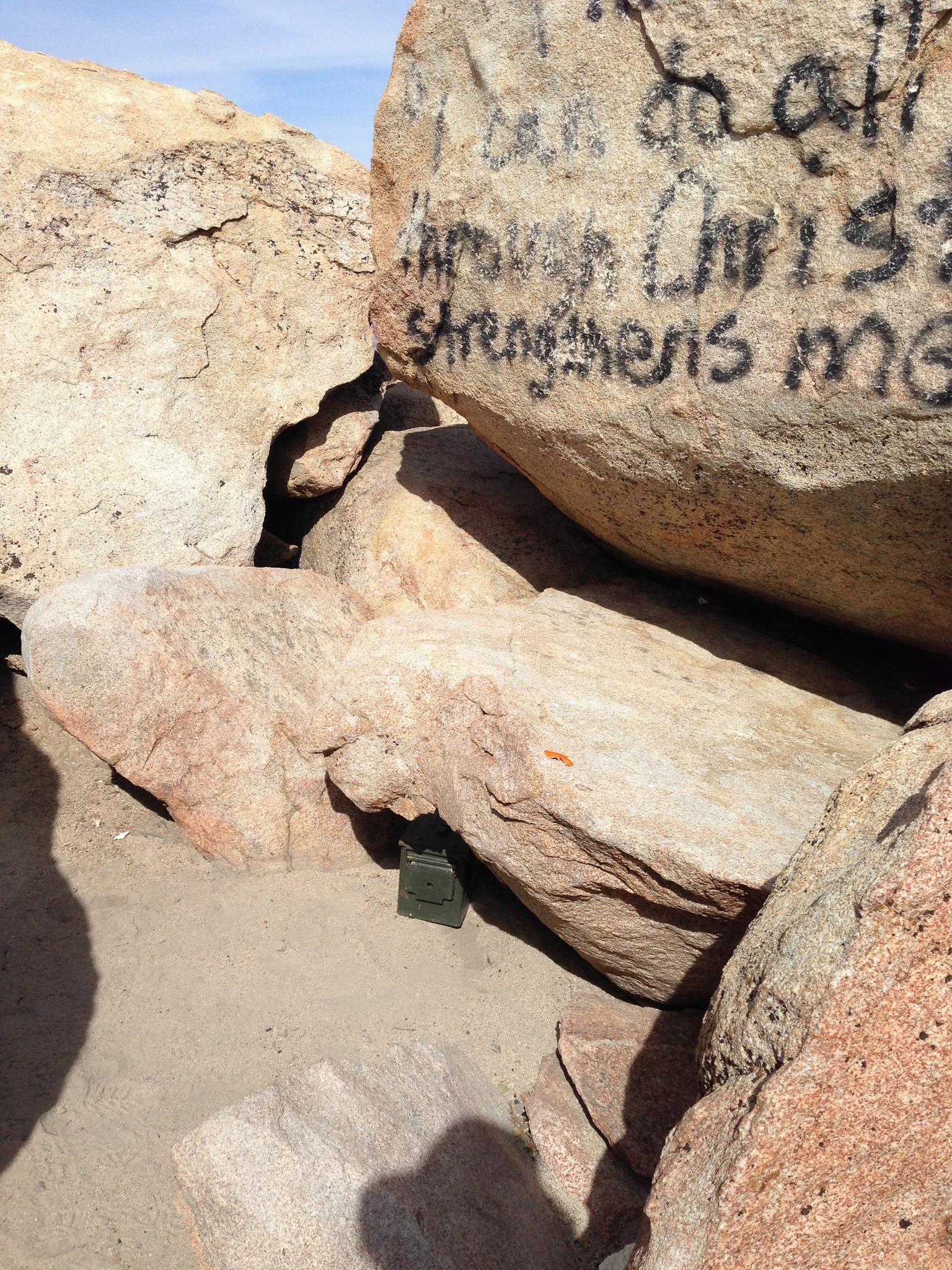 Close-up of large boulders with graffiti and a small green box.