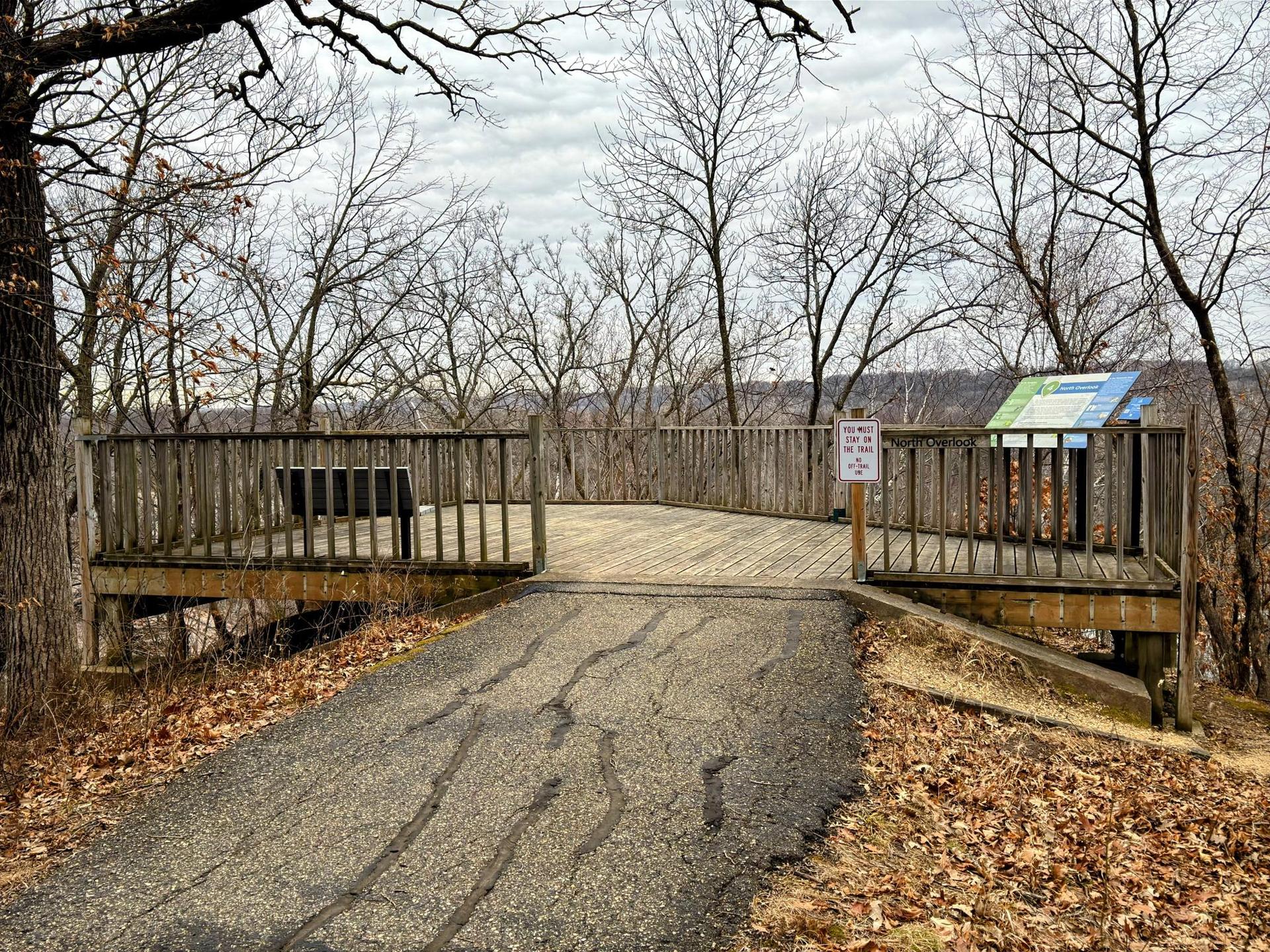 Wooden observation deck overlooking a valley, surrounded by bare trees.